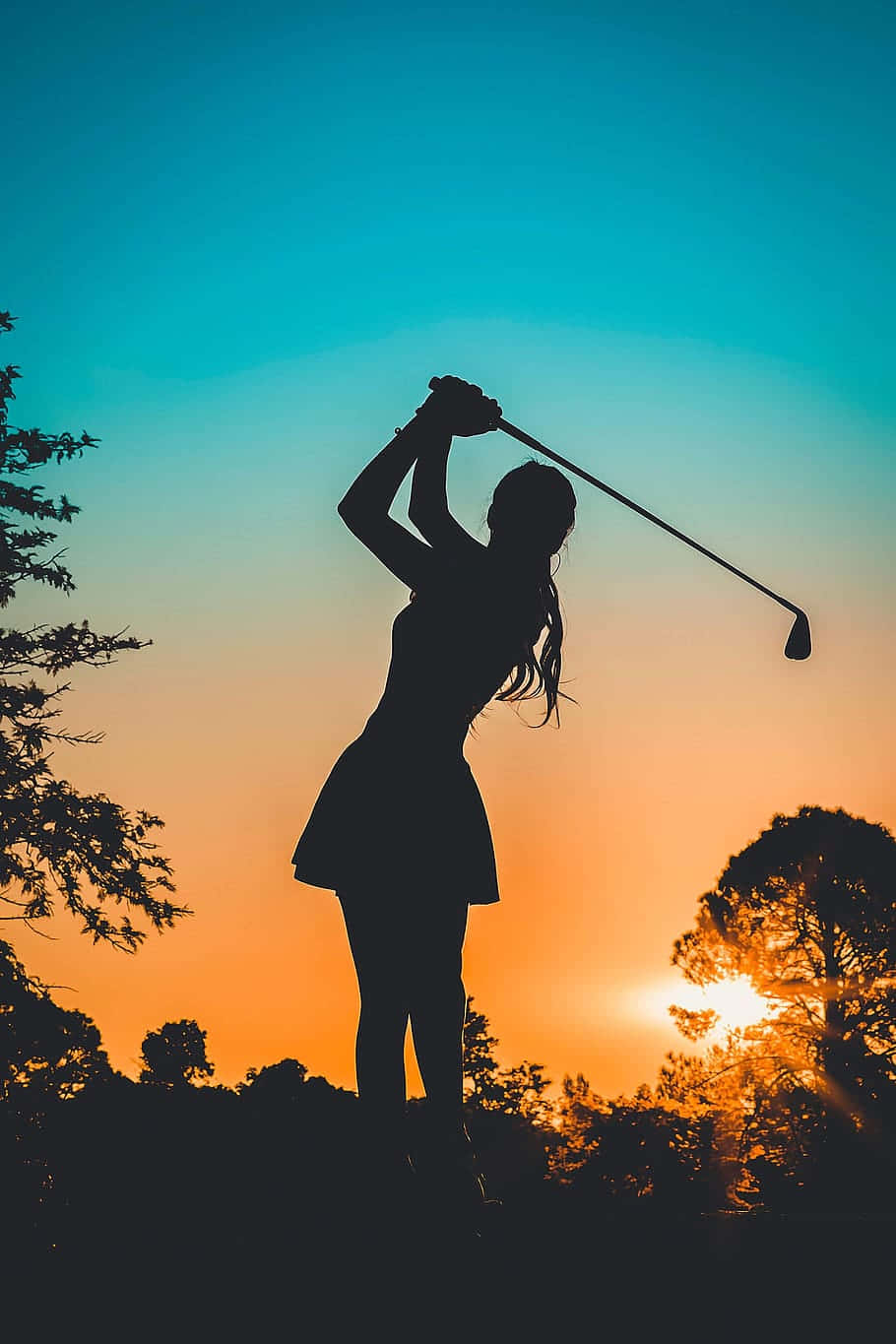 Silhouette 桌布 壁紙 — 高爾夫球手揮桿中的剪影，背景是充滿活力的日落天空，樹木框住場景。