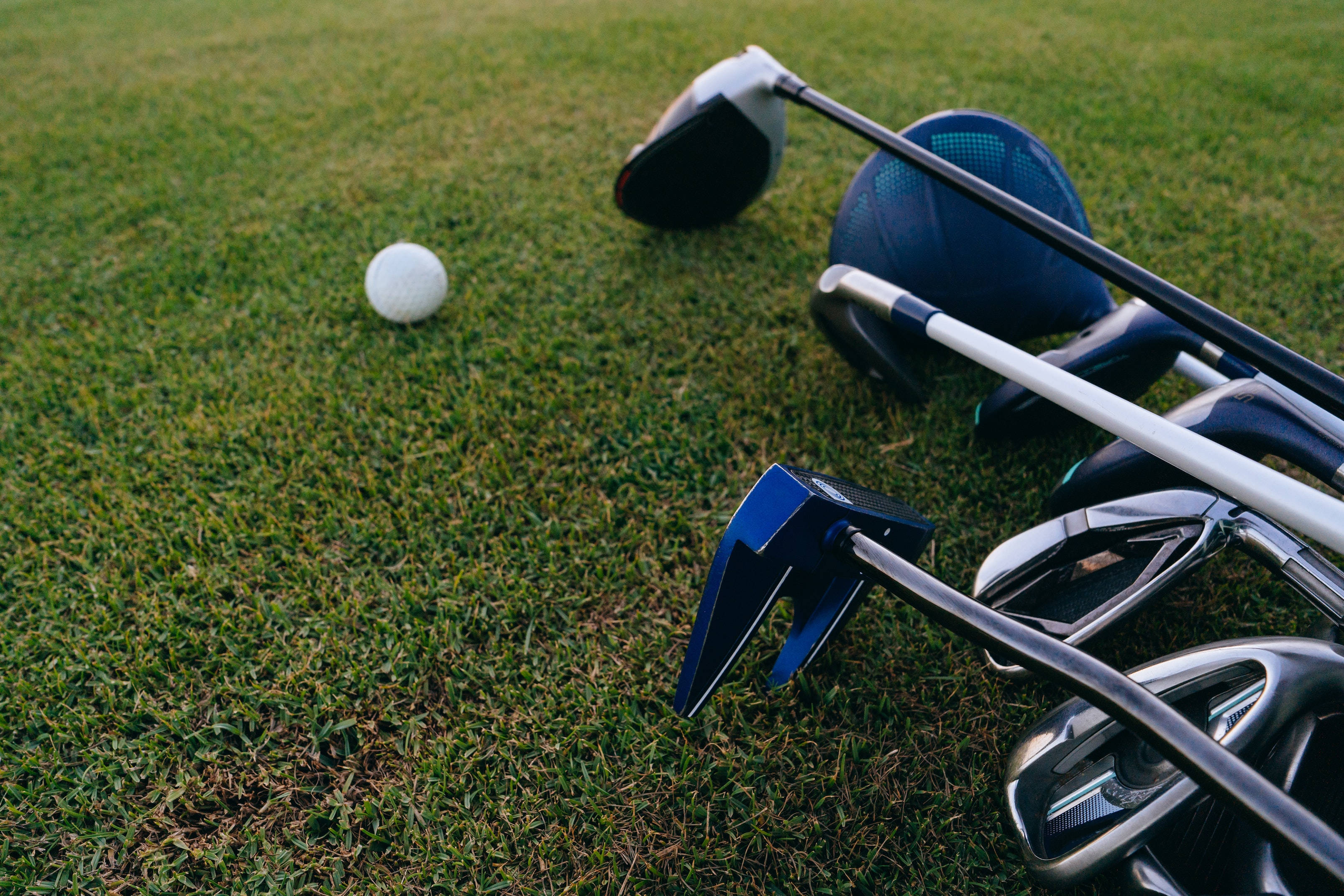 4K Golf 桌布 壁紙 — 高爾夫球桿和高爾夫球在柔和日光下放在充滿活力的綠色草地上。