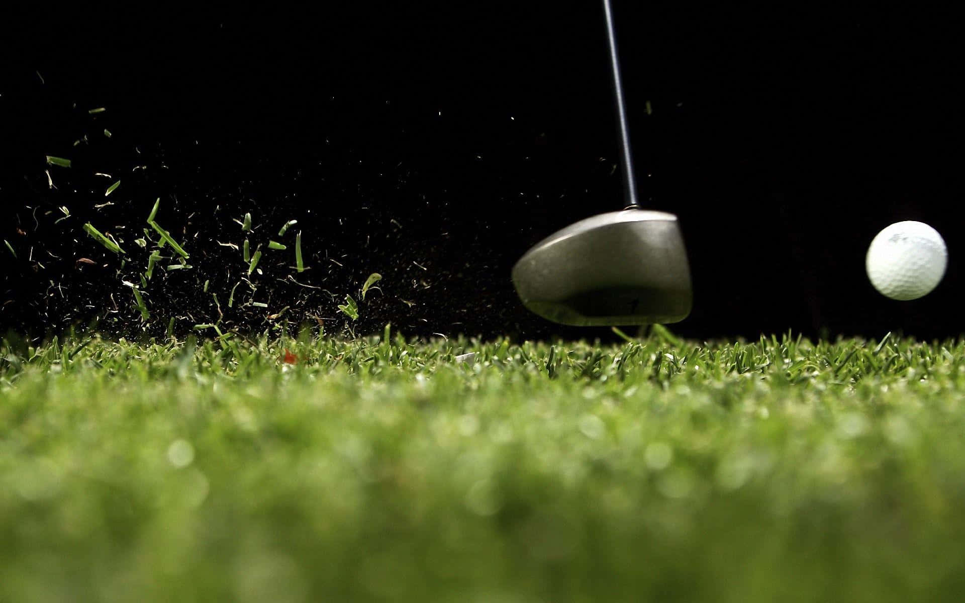 Awesome Golf 桌布 壁紙 — 高爾夫球桿在鮮綠色草地上擊球，草葉飛舞，背景為純黑色。