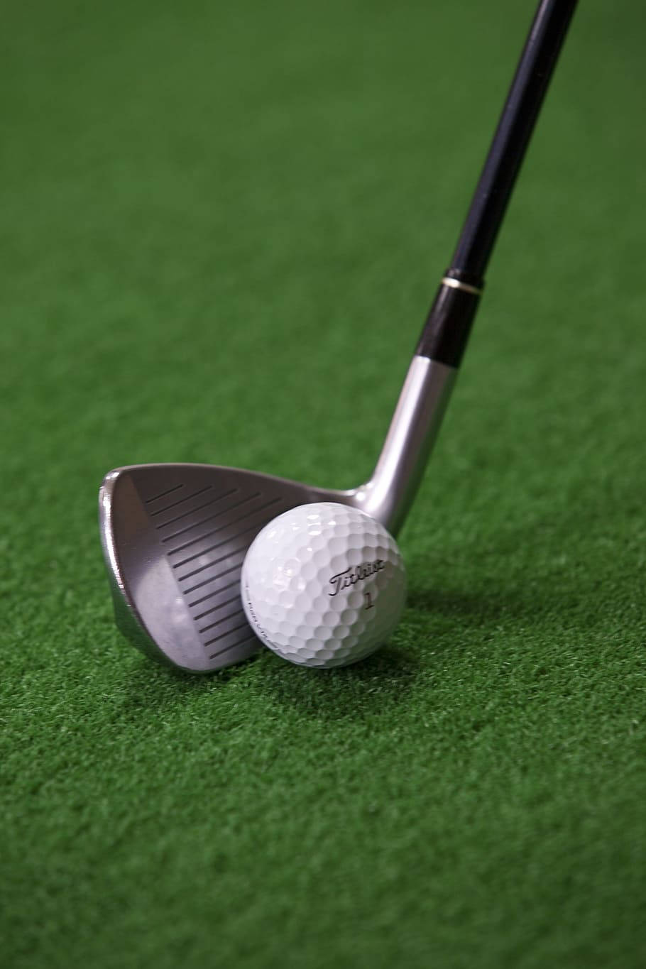 高爾夫 桌布 壁紙 — 高爾夫球桿頭的特寫，旁邊放著一個白色的 Titleist 高爾夫球，背景是充滿活力的綠色草坪。