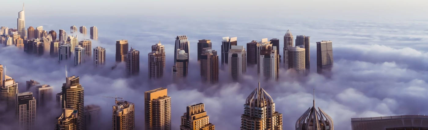Skyscraper 桌布 壁紙 — 高空俯瞰摩天大樓穿透厚厚雲層的景觀，日出時金色光芒照亮城市天際線。