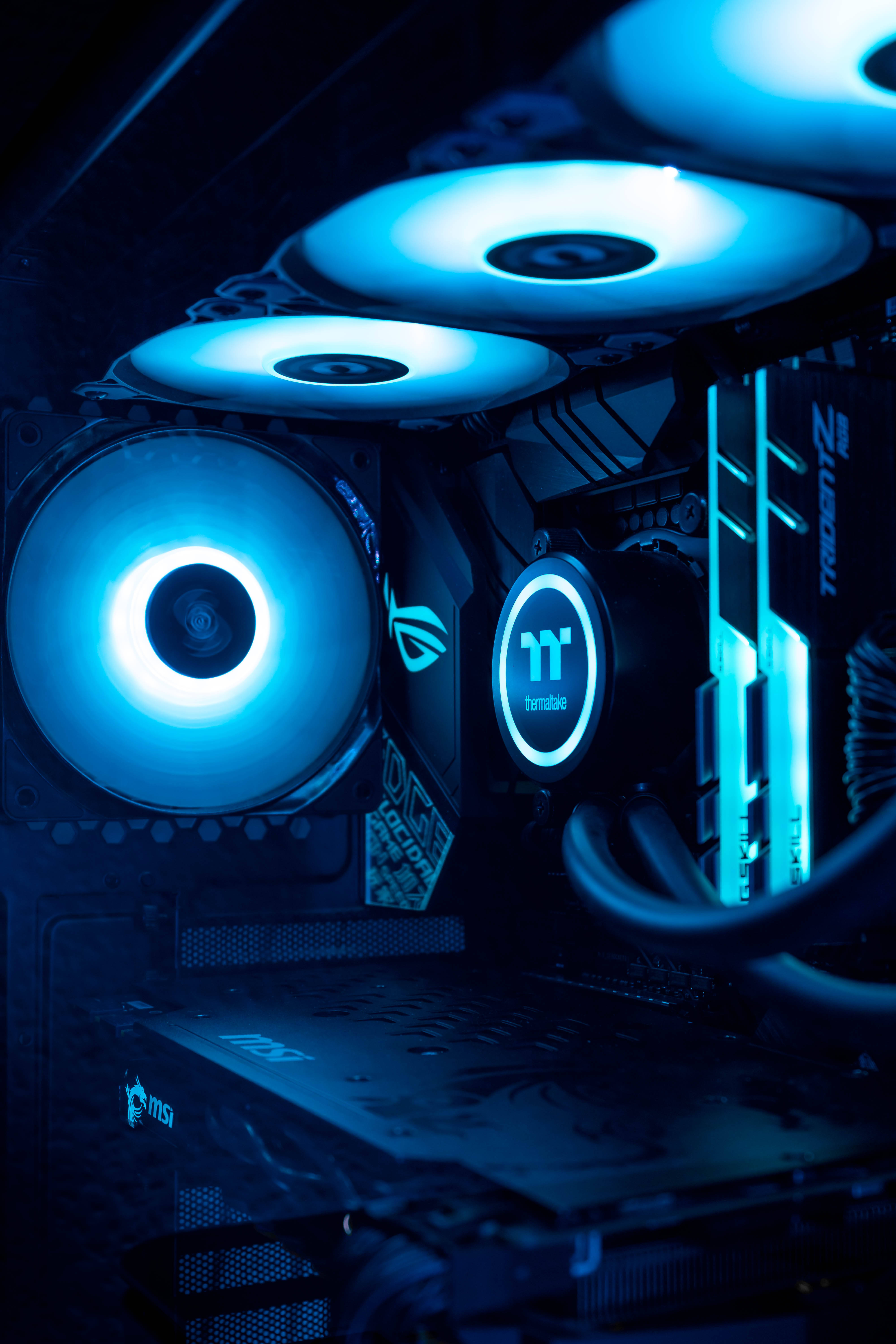 msi 2560x1080 桌布 壁紙 — 高端遊戲電腦內部特寫，沐浴在風扇和組件發出的冷藍色LED燈光中。