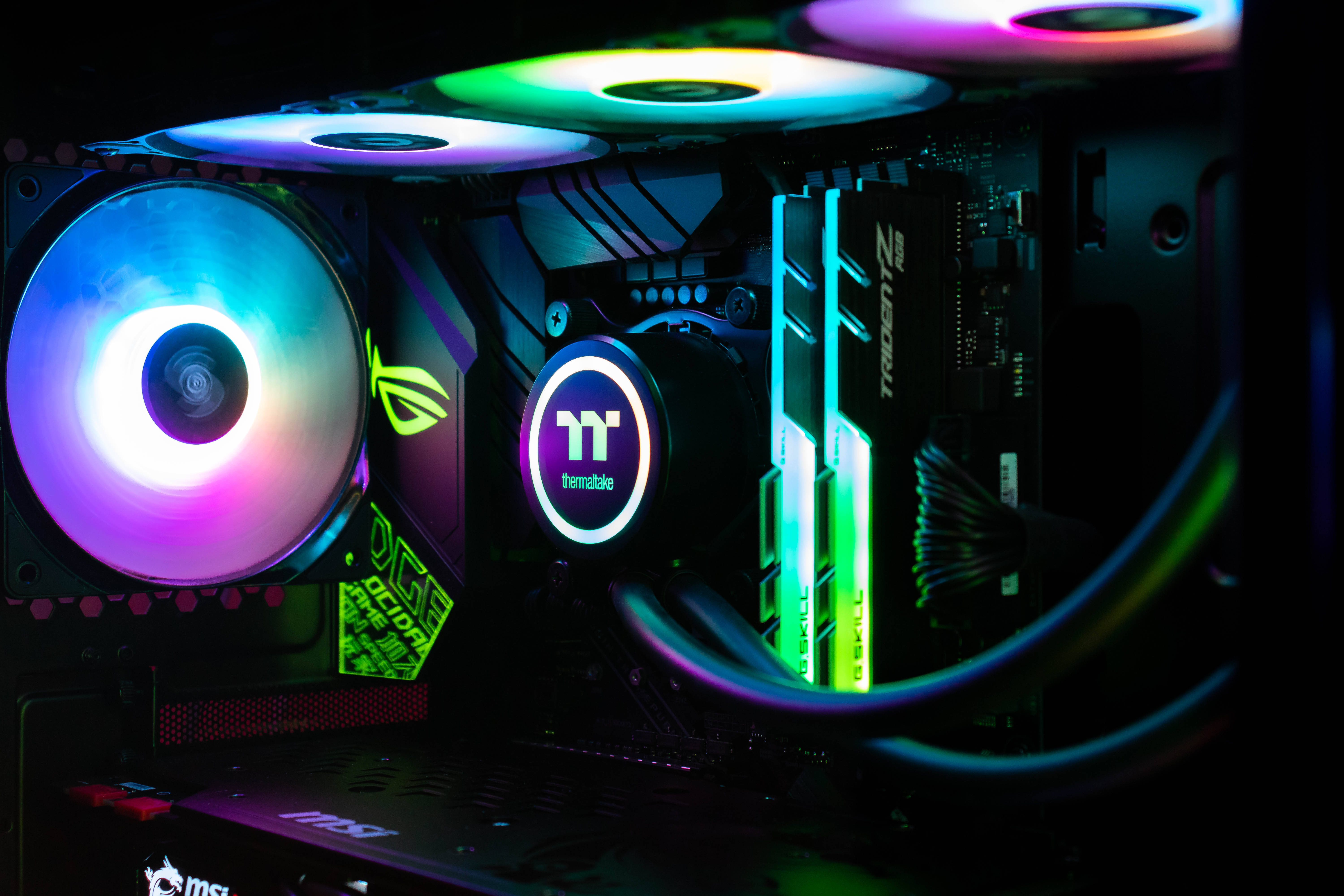 msi 2560x1080 桌布 壁紙 — 高端遊戲電腦內部特寫，風扇和RAM條上閃爍著鮮豔的彩虹LED燈光。