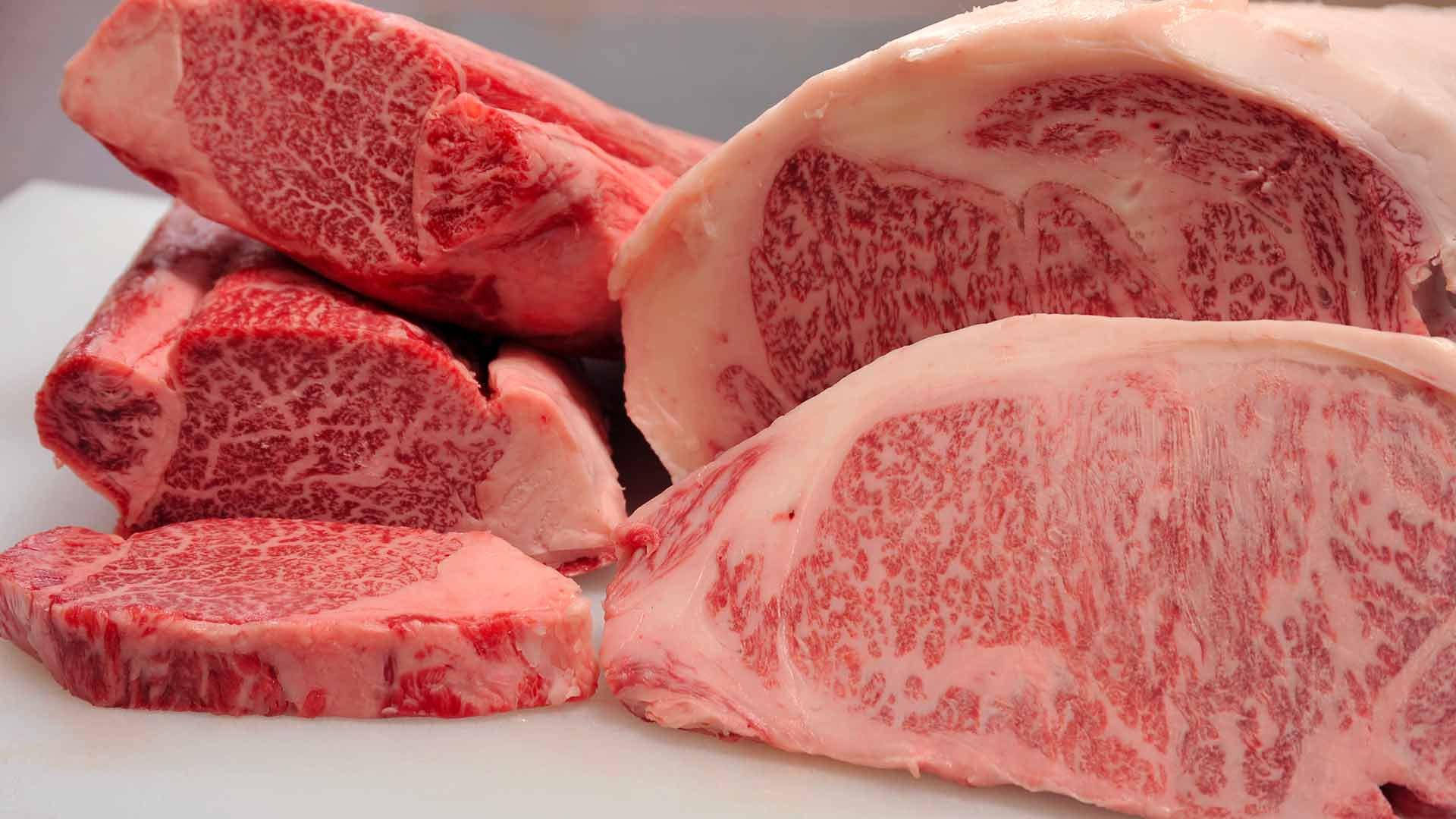 meat 桌布 壁紙 — 高級大理石紋牛肉切塊的特寫，在潔白的表面上展現豐富的紅肉和複雜的白色脂肪紋理。