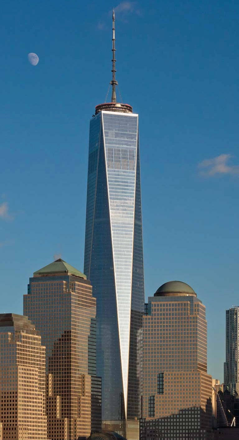 Blue Sky 桌布 壁紙 — 高聳的One World Trade Center在清澈藍天下閃耀，上方有新月，周圍摩天大樓沐浴在金色陽光中。