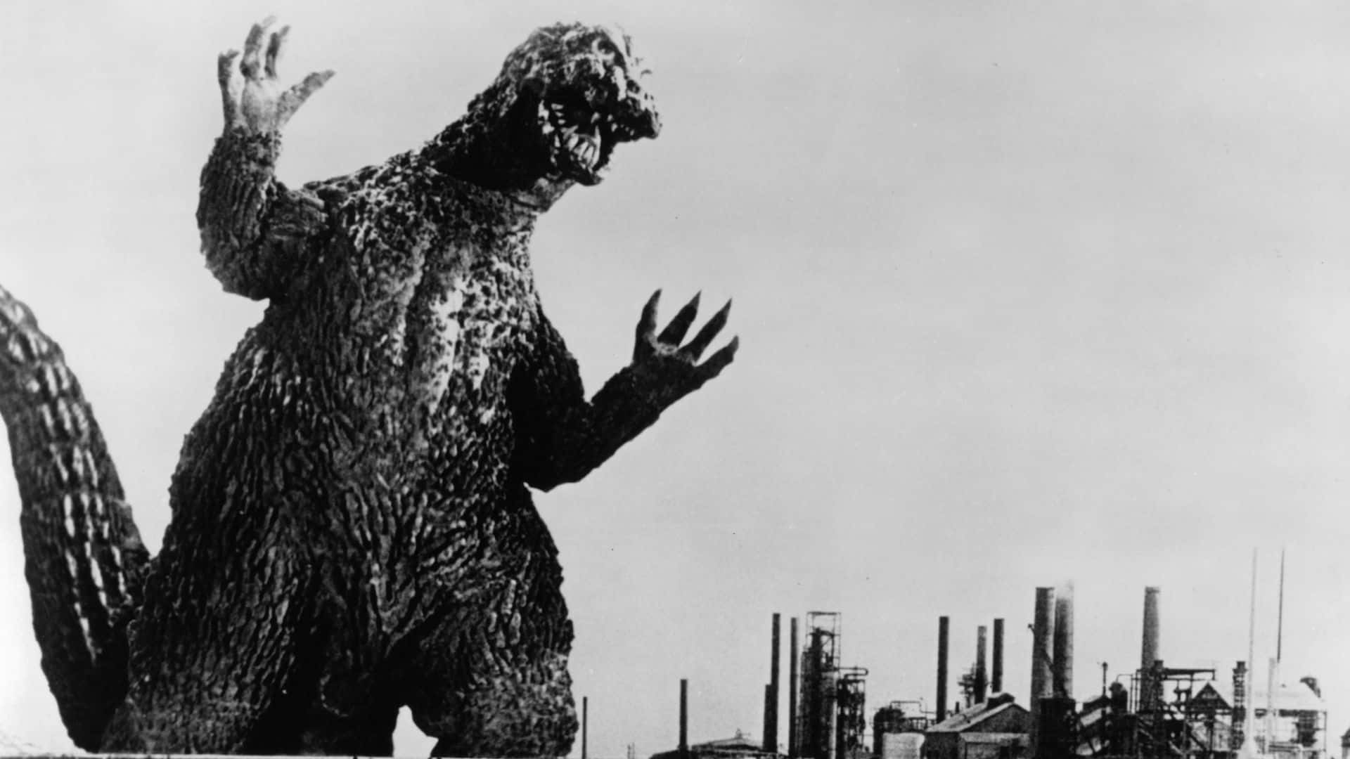 Classic Godzilla 桌布 壁紙 — 高聳的哥吉拉在戲劇性的黑白照片中，威嚇地站在有煙囪的工業城市景觀之上。
