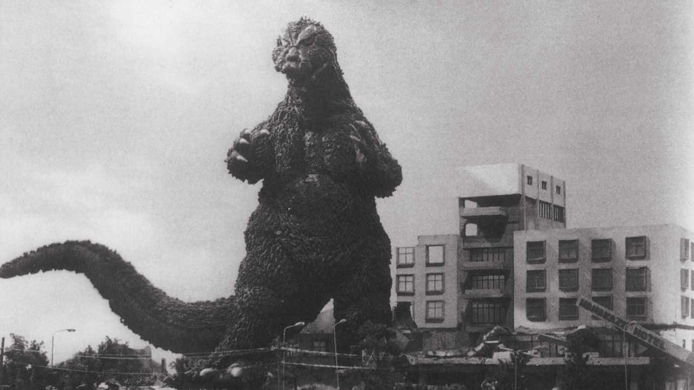 Godzilla 1954 桌布 壁紙 — 高聳的哥吉拉站在被摧毀的城市建築物中，形成戲劇性的黑白場景。