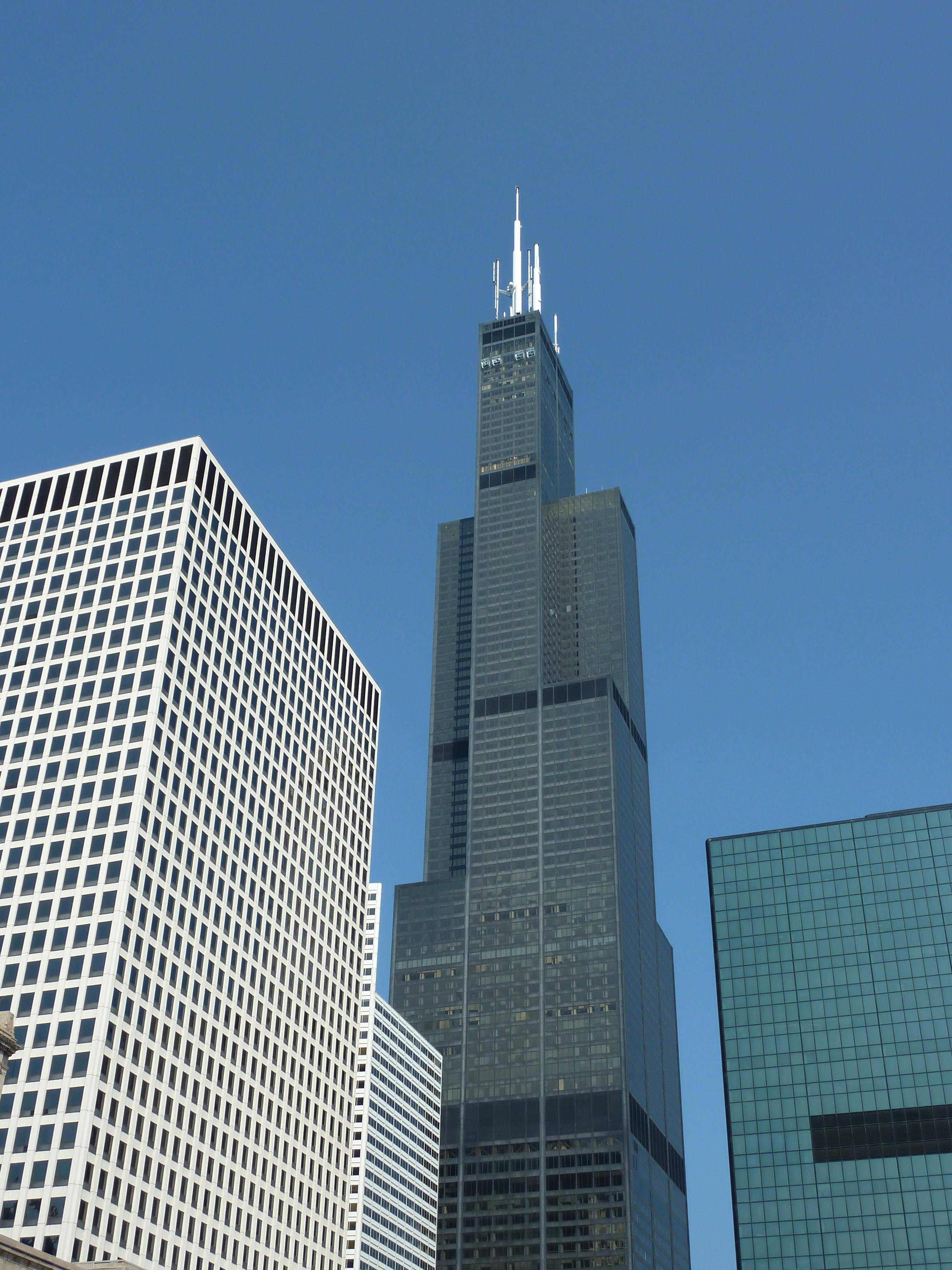 tower 桌布 壁紙 — 高聳的威利斯大廈刺穿芝加哥城市天際線上方清澈的藍天，周圍環繞著玻璃和鋼鐵摩天大樓。