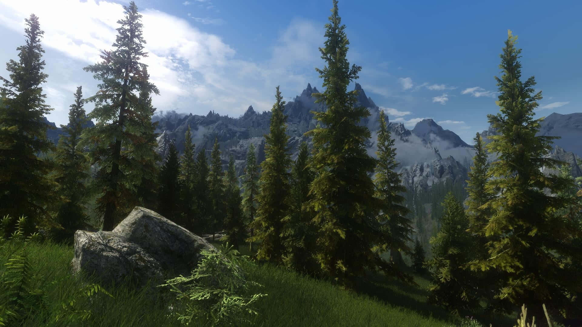 Skyrim Falkreath 桌布 壁紙 — 高聳的常綠樹在明亮的藍天和零星白雲下，框住雄偉的積雪山脈。
