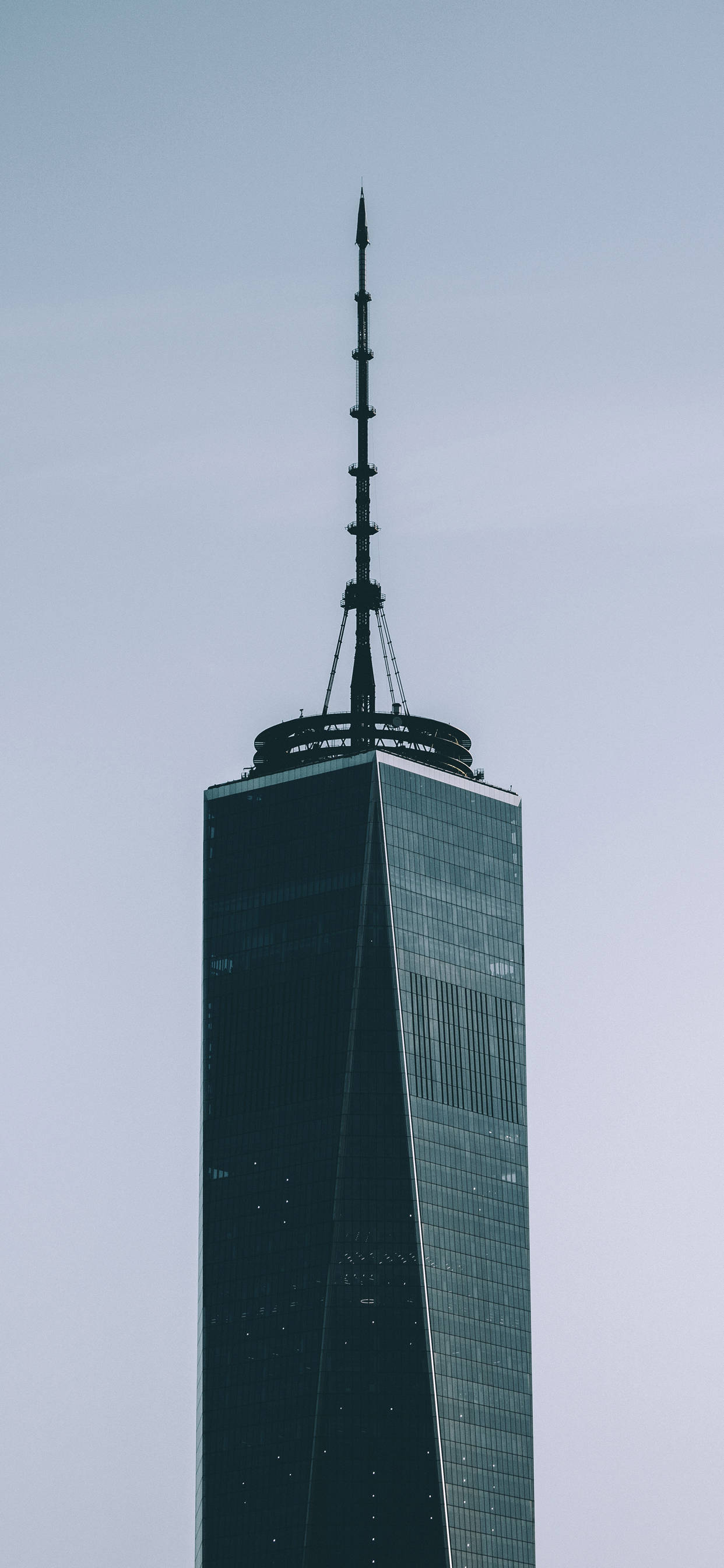Skyscraper 桌布 壁紙 — 高聳的摩天大樓，玻璃外牆和尖頂刺穿蒼白的天空，極簡主義城市拍攝。