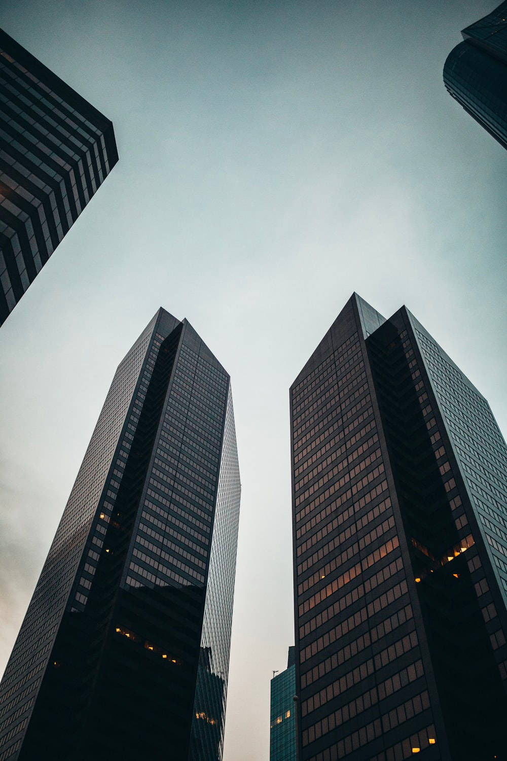 Skyscraper 桌布 壁紙 — 高聳的摩天大樓以玻璃幕牆刺穿柔和的天空，反射出內部的暮色燈光。