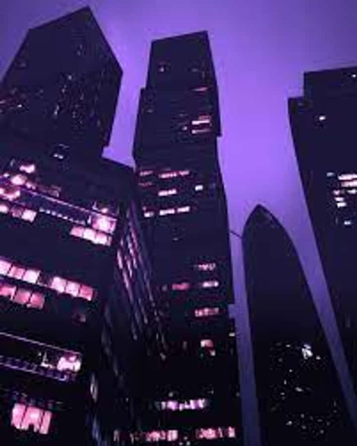 夜空 桌布 壁紙 — 高聳的摩天大樓刺穿深紫色的暮色天空，發光的窗戶照亮了下面的城市峽谷。