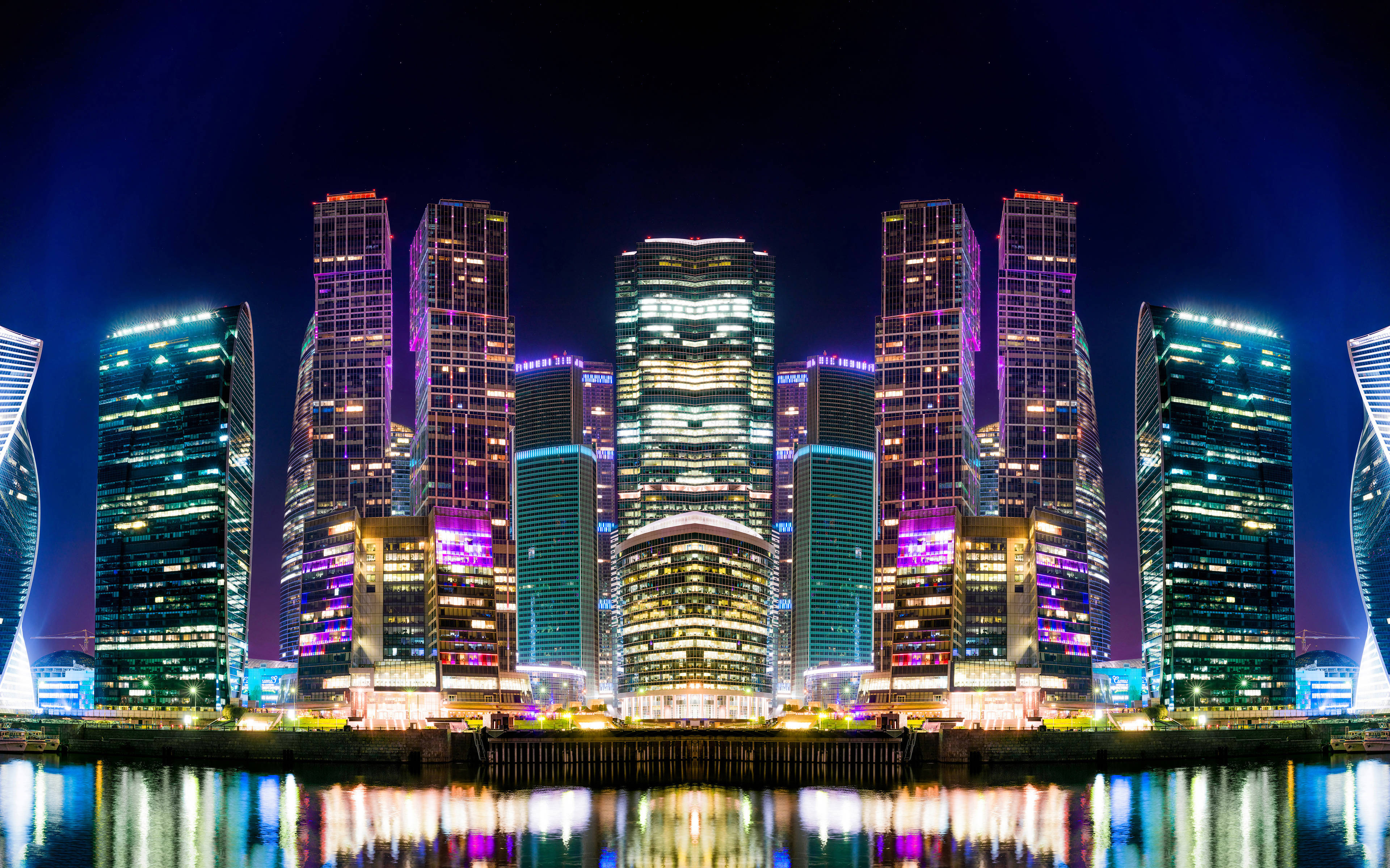 Russia 桌布 壁紙 — 高聳的摩天大樓閃爍著鮮豔的霓虹燈光，在深邃的夜空下平靜的水面上倒映。