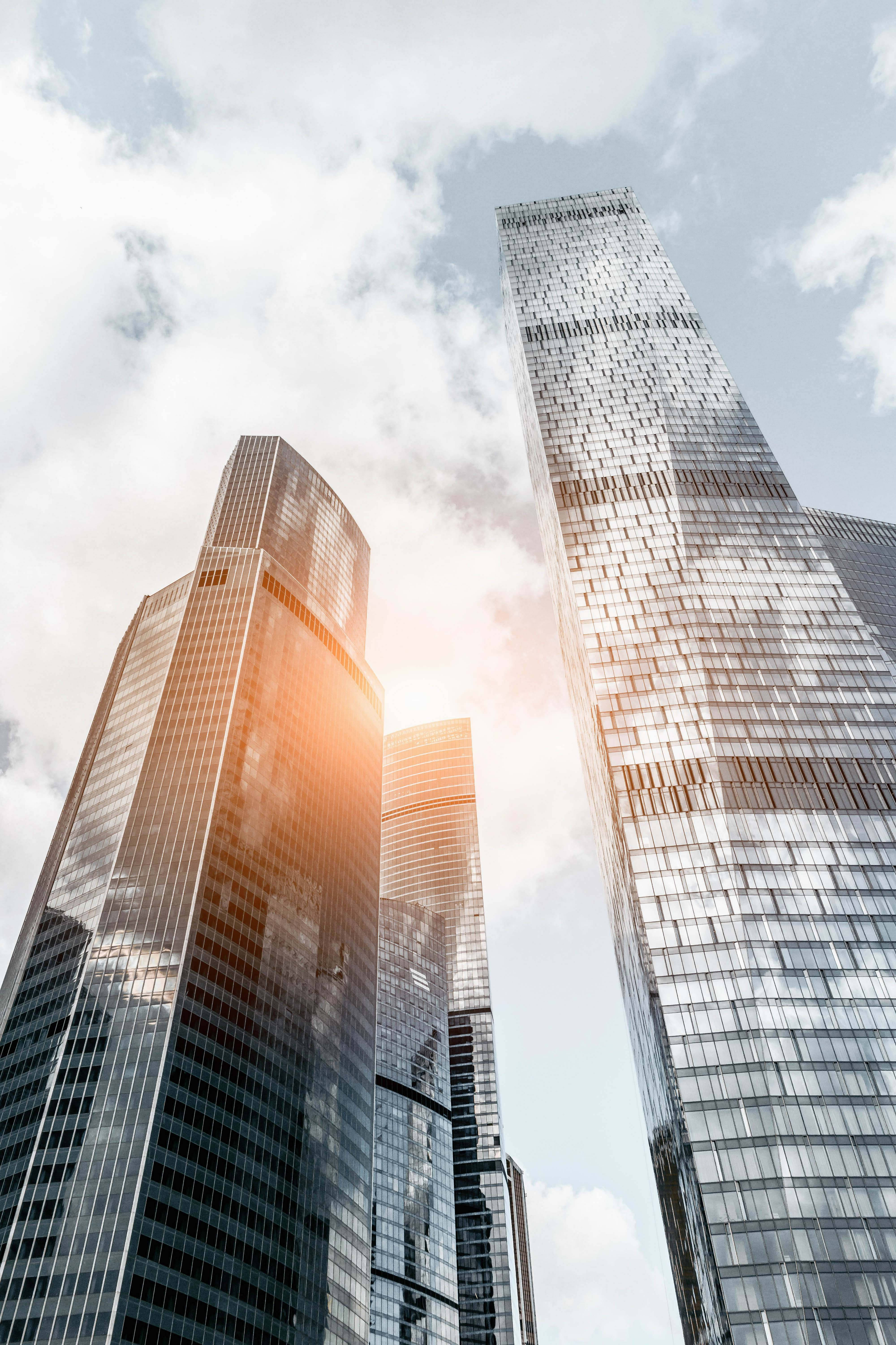 Moscow 桌布 壁紙 — 高聳的玻璃摩天大樓刺穿明亮的天空，太陽在其現代鋼框架之間閃耀。