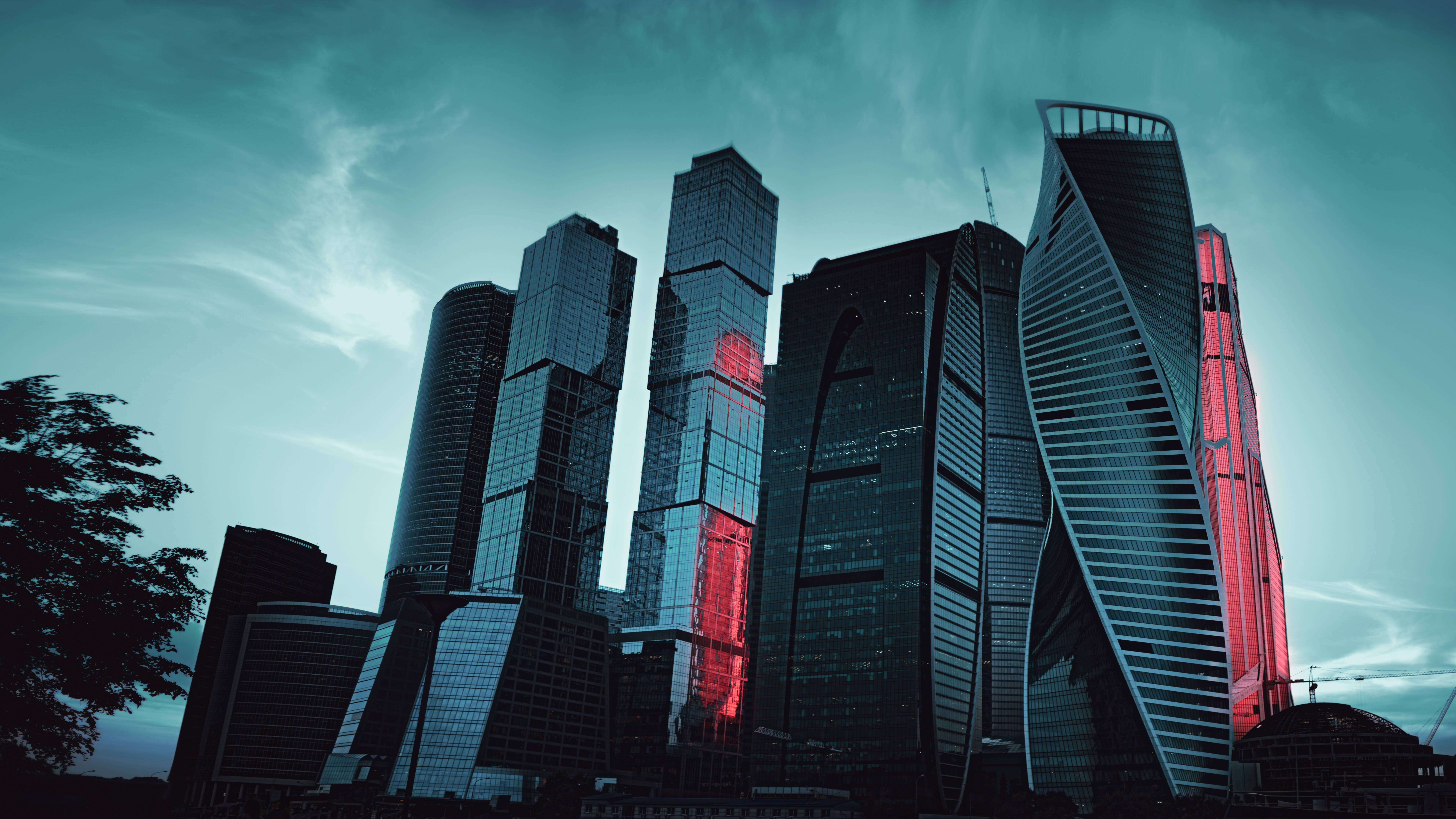 Moscow 桌布 壁紙 — 高聳的玻璃摩天大樓刺穿青綠色的暮色天空，大膽的紅色照明點綴在黑暗的外牆上閃耀。