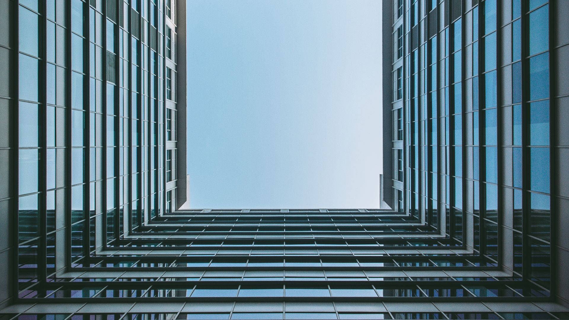 Modern 桌布 壁紙 — 高聳的玻璃摩天大樓在戲劇性的低角度城市鏡頭中框出清澈的藍天。