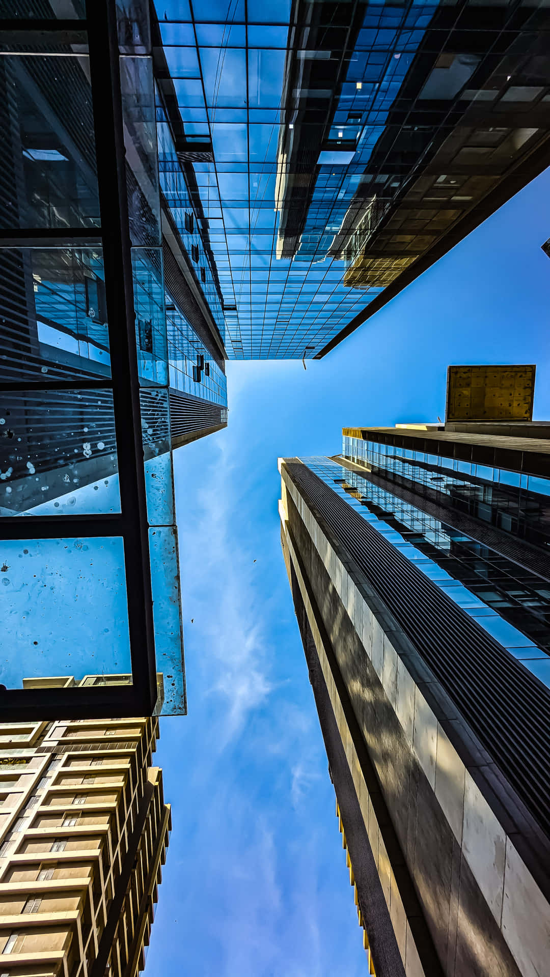 ARCHITECTURE 壁紙 — 高聳的玻璃摩天大樓在戲劇性的低角度城市拍攝中，框住了充滿活力的藍天和縷縷白雲。