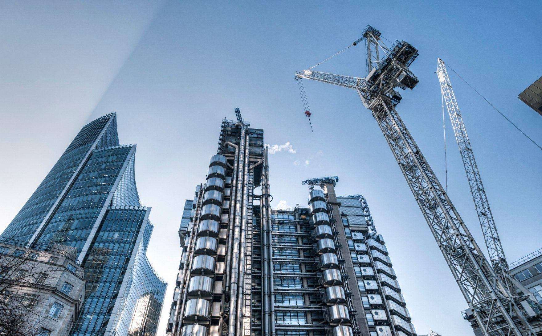 construction 桌布 壁紙 — 高聳的現代摩天大樓和建築起重機在繁華的城市天際線中佔據了明亮的藍天。