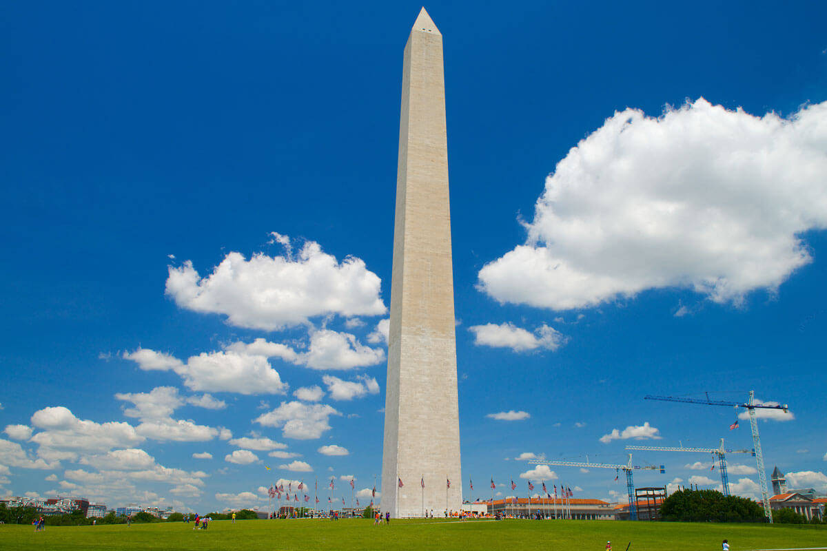 Washington 桌布 壁紙 — 高聳的白色華盛頓紀念碑在晴朗的日子裡，襯著點綴著蓬鬆白雲的鮮豔藍天高高聳立。