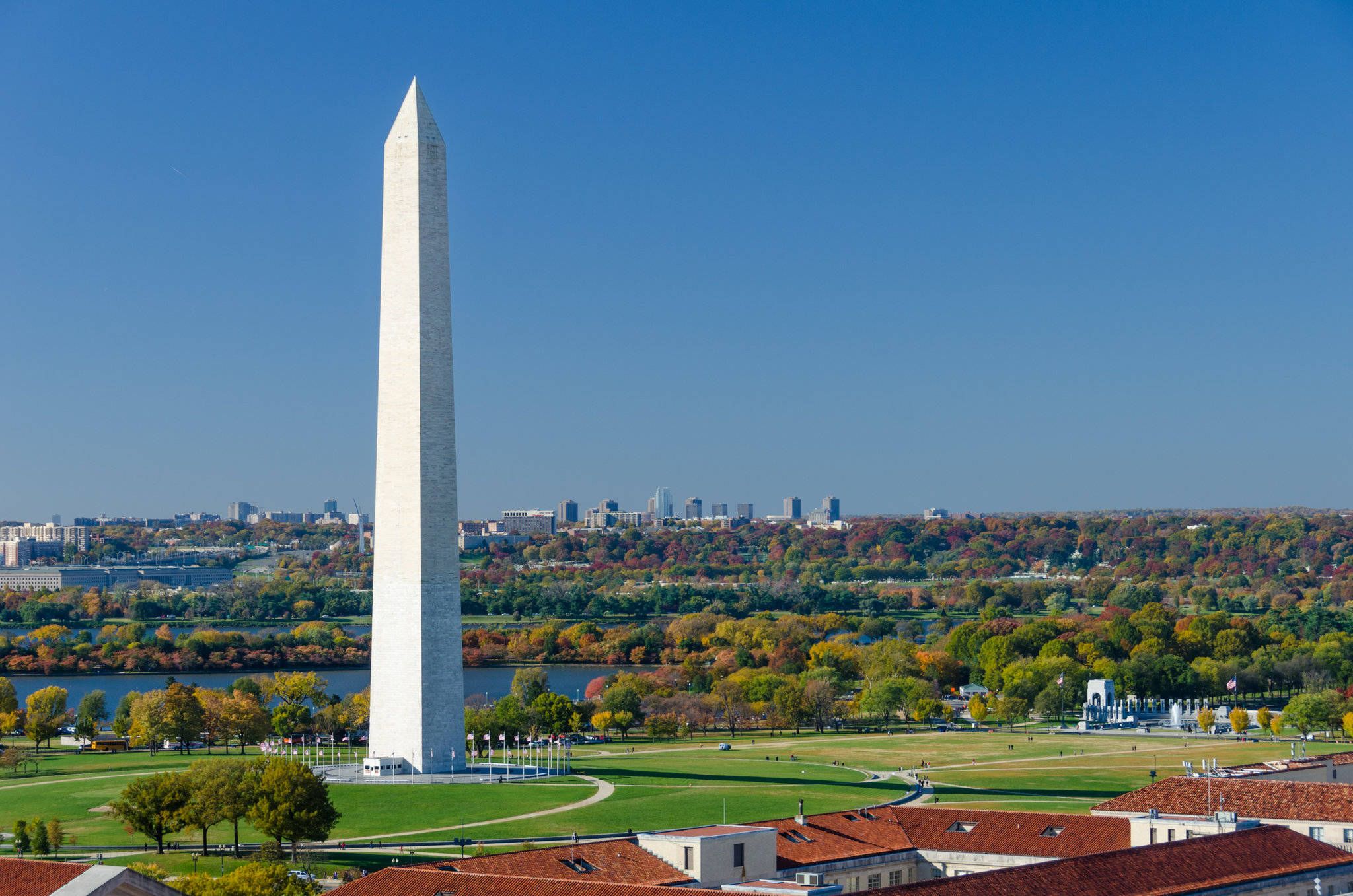 Washington 桌布 壁紙 — 高聳的華盛頓紀念碑在晴朗的藍天下矗立，遠處有秋樹和城市天際線。