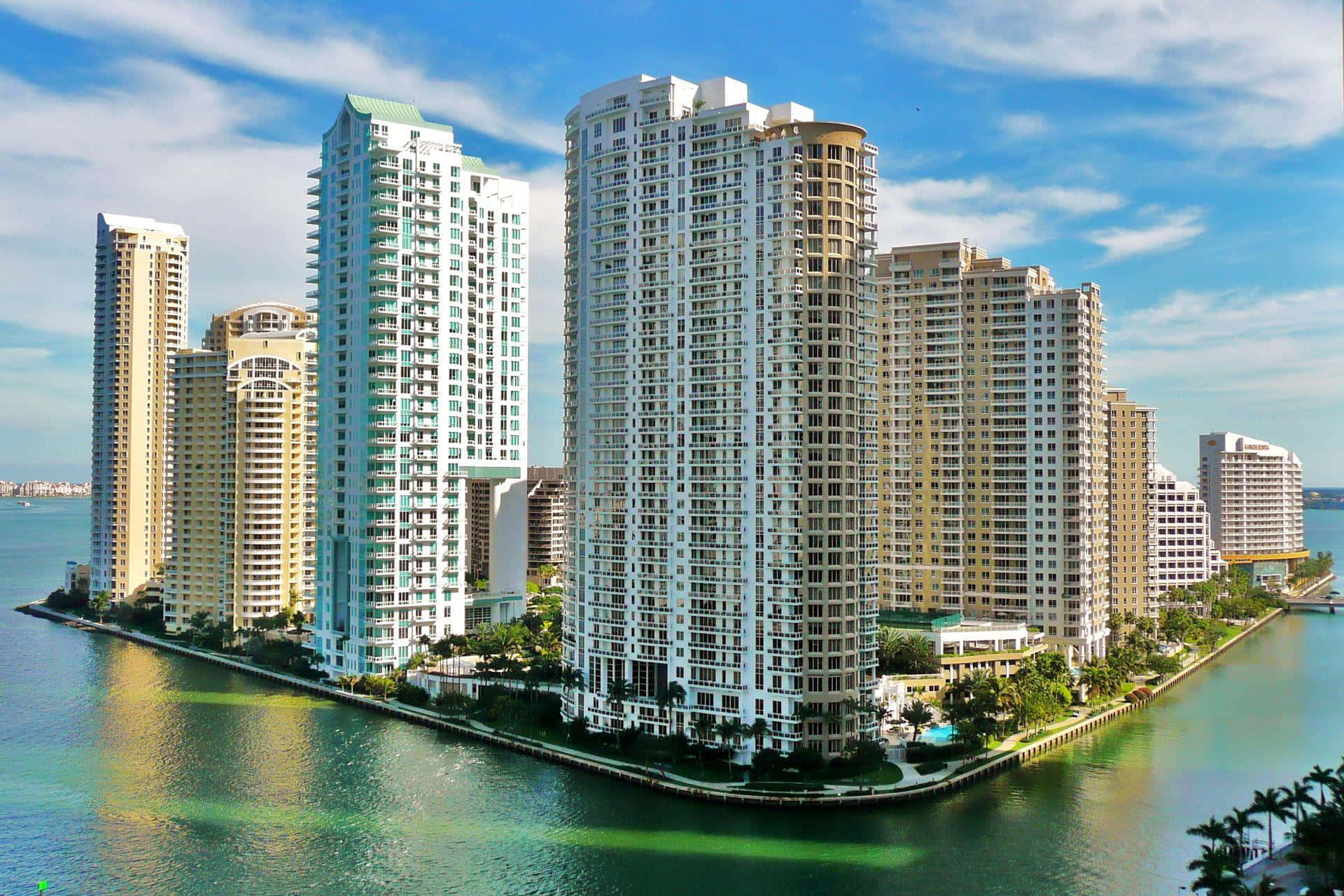 Buildings 桌布 壁紙 — 高聳的豪華摩天大樓沿著海濱運河排列，上方是明亮的藍天，點綴著幾朵白雲。