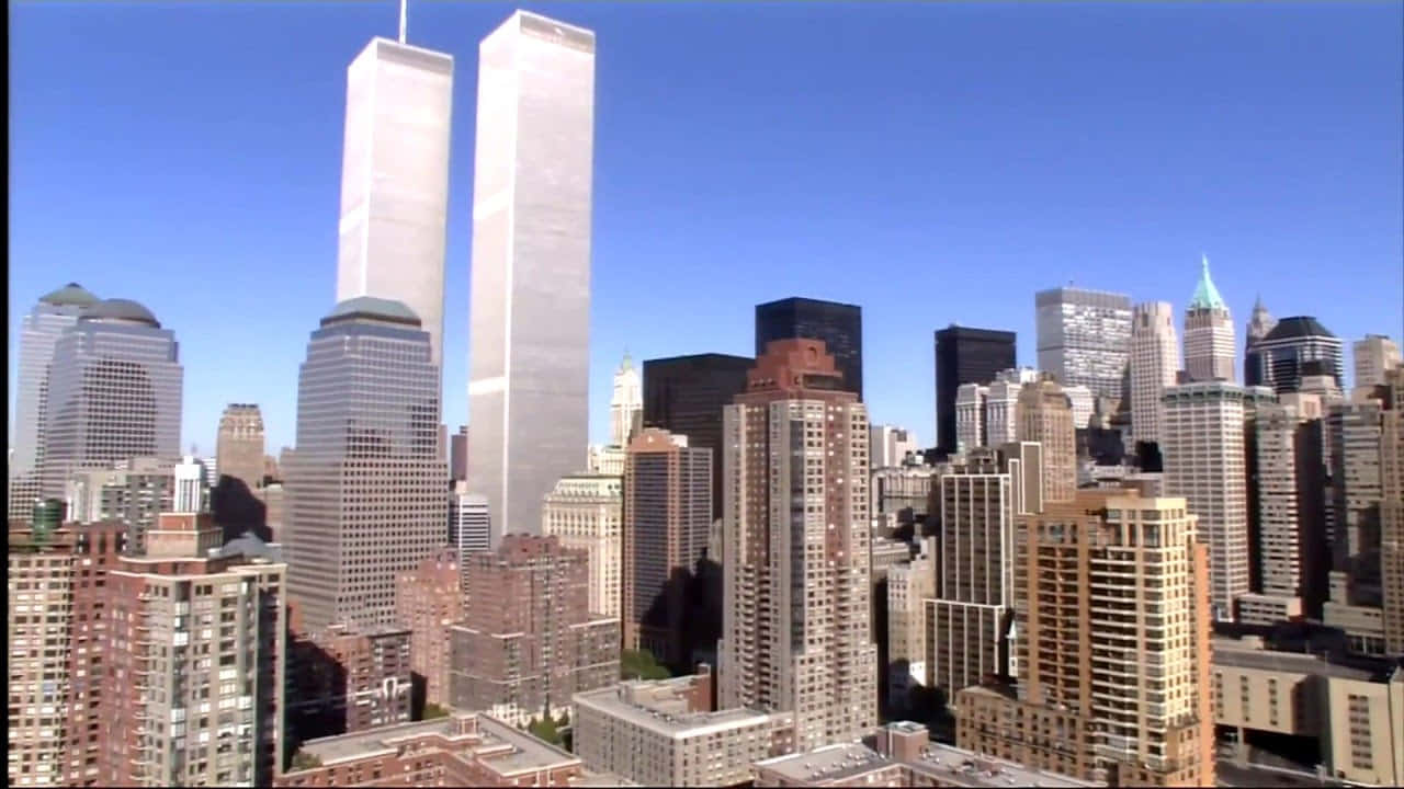 720p Ny City 桌布 壁紙 — 高聳的雙子塔在晴朗的藍天下，連同周圍的現代建築，主宰著密集的城市天際線。