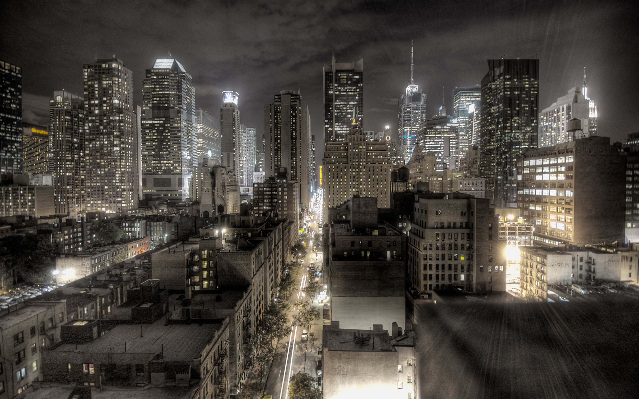 City Night 桌布 壁紙 — 高角度夜景，密集的城市天際線，有燈光閃爍的摩天大樓和發光的街燈。