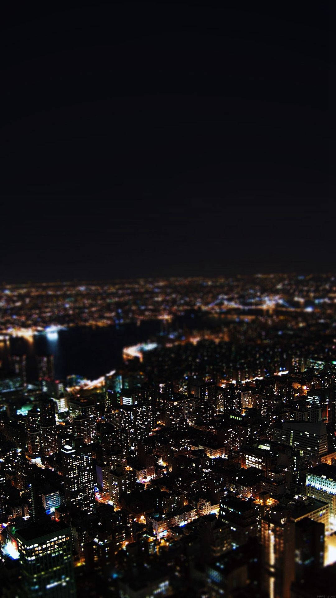 手機 桌布 壁紙 — 高角度夜景，展現廣闊城市景觀，溫暖人造燈光在黑暗天空中閃爍。