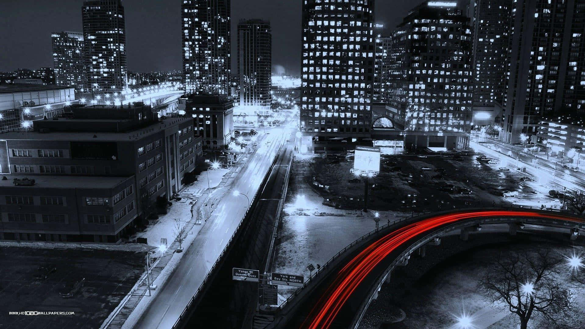 1080p Winter 桌布 壁紙 — 高角度夜間城市景觀，有積雪街道和彎曲高速公路上的鮮紅色光跡。
