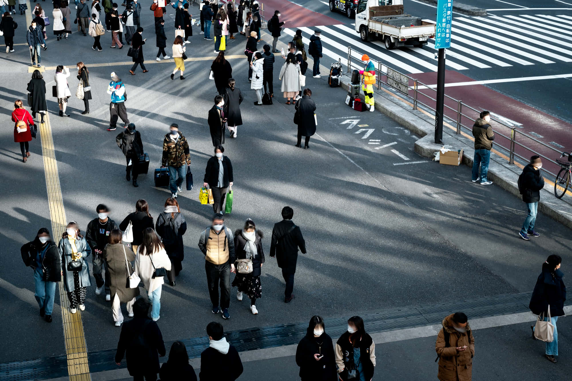 日本 桌布 壁紙 — 高角度拍攝擁擠的行人穿越繁忙的城市街道，帶有長長的陰影和附近的一輛卡車。