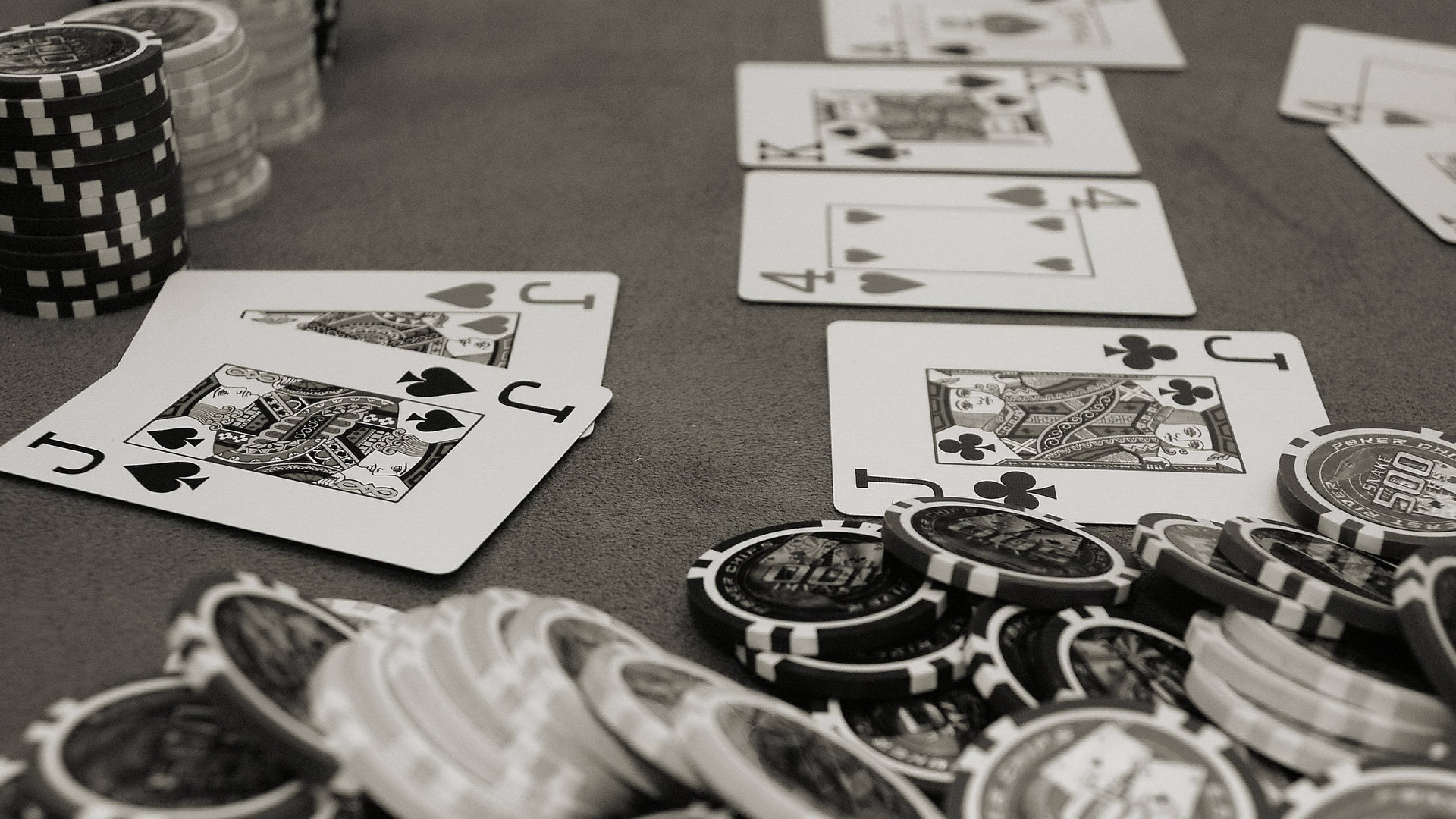 Poker 桌布 壁紙 — 高風險賭局中，綠色絨布桌上籌碼與翻開紙牌的黑白特寫。