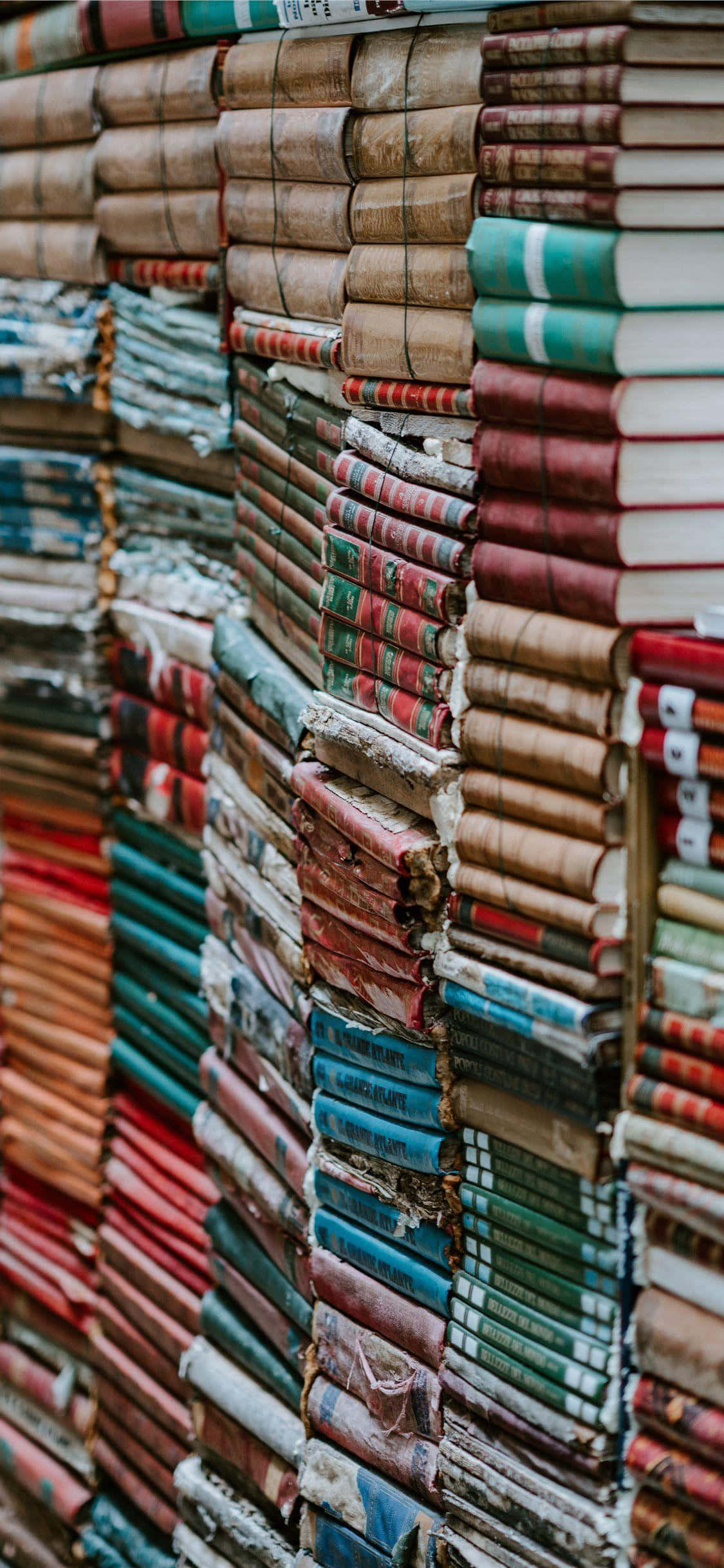 books 桌布 壁紙 — 高高的復古書堆，磨損的彩色書脊形成了一面有質感的文學牆。