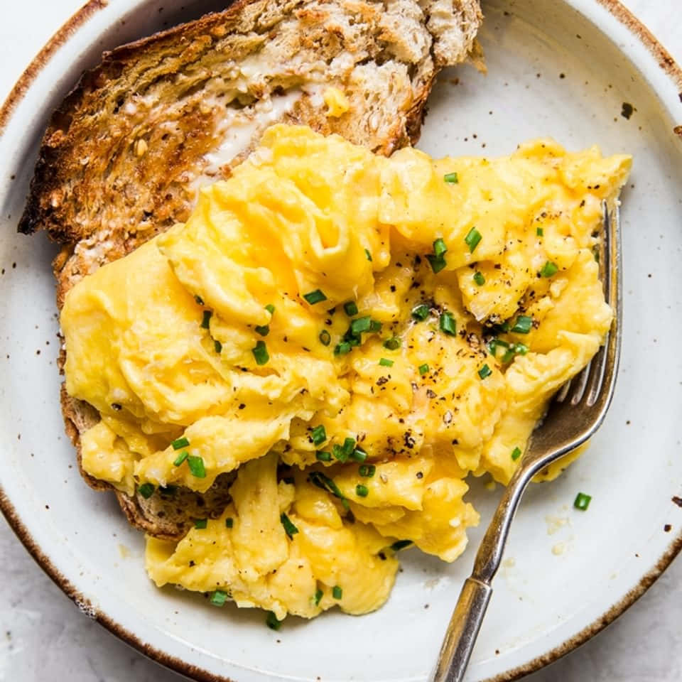 Scrambled Egg 桌布 壁紙 — 鬆軟炒蛋搭配細香蔥和黑胡椒，放在烤酸種麵包上，置於斑點陶瓷盤中。
