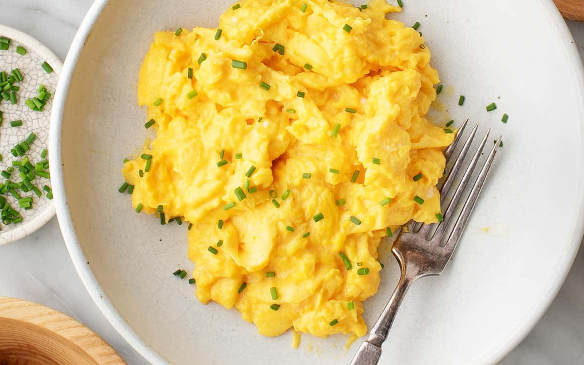 Scrambled Egg 桌布 壁紙 — 鬆軟金黃色炒蛋，飾以新鮮青蔥，盛載於白色陶瓷碗中，附有叉子。