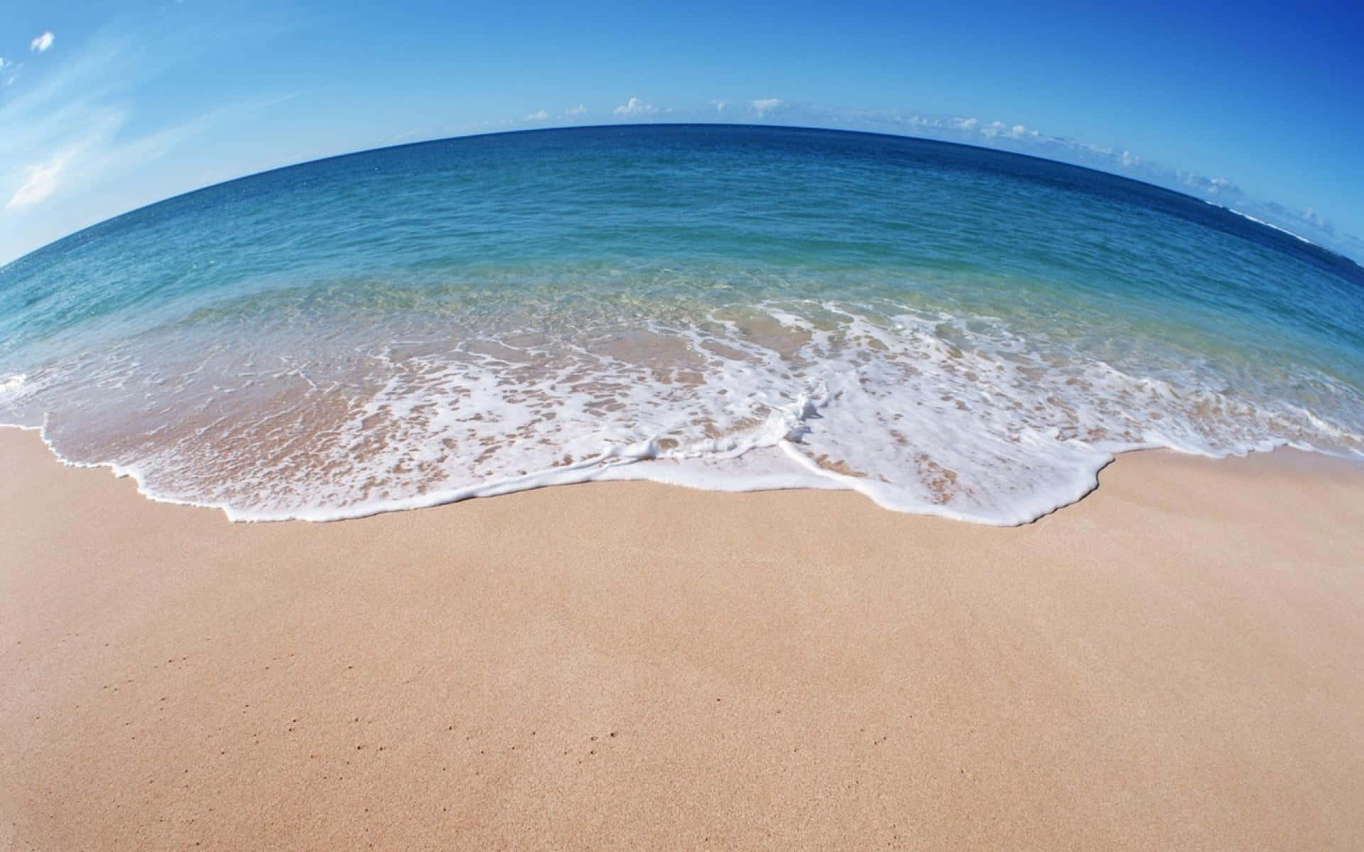 Ocean Waves 桌布 壁紙 — 魚眼視角：在清澈藍天下，碧綠海浪拍打金色沙灘。