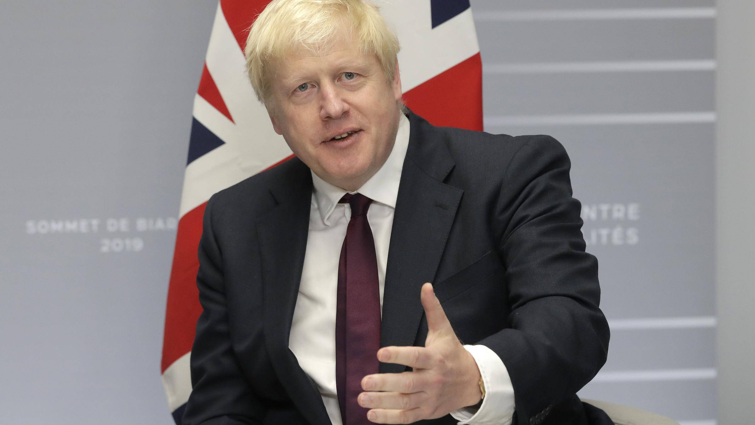Boris Johnson 桌布 壁紙 — 鮑里斯·強森在2019年比亞里茨峰會新聞發布會上發言時做手勢，身後有英國國旗。