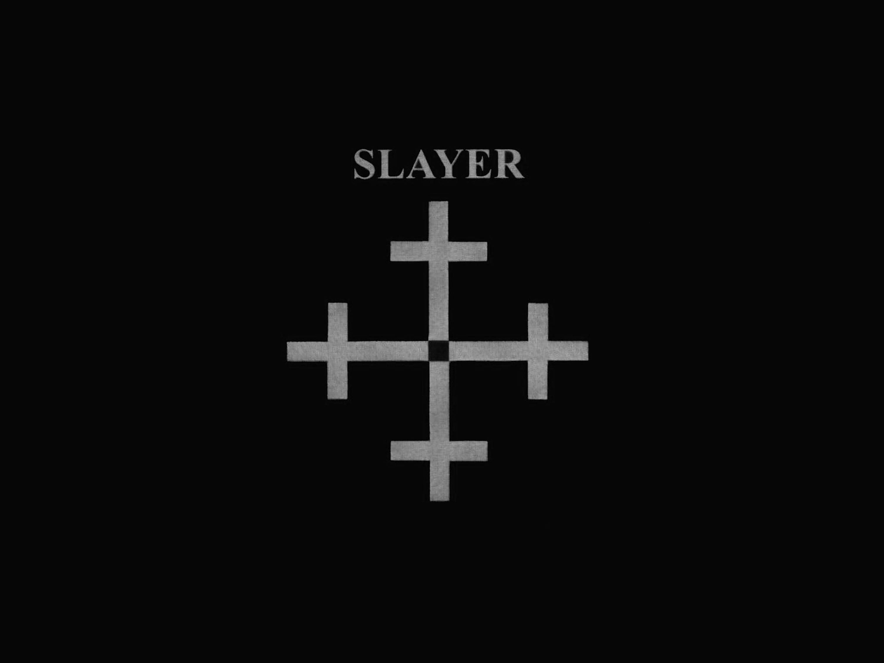 Slayer 桌布 壁紙 — 鮮明的黑色背景上，SLAYER 一字位於一個金屬十字符號（有四臂和中央正方形）之上。