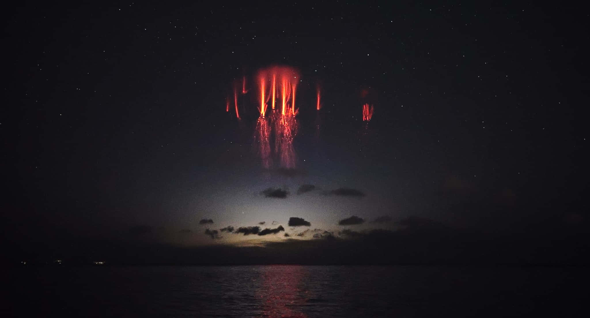風景 桌布 壁紙 — 鮮紅的熔岩流從火山傾瀉入海，在繁星點點的夜空下。