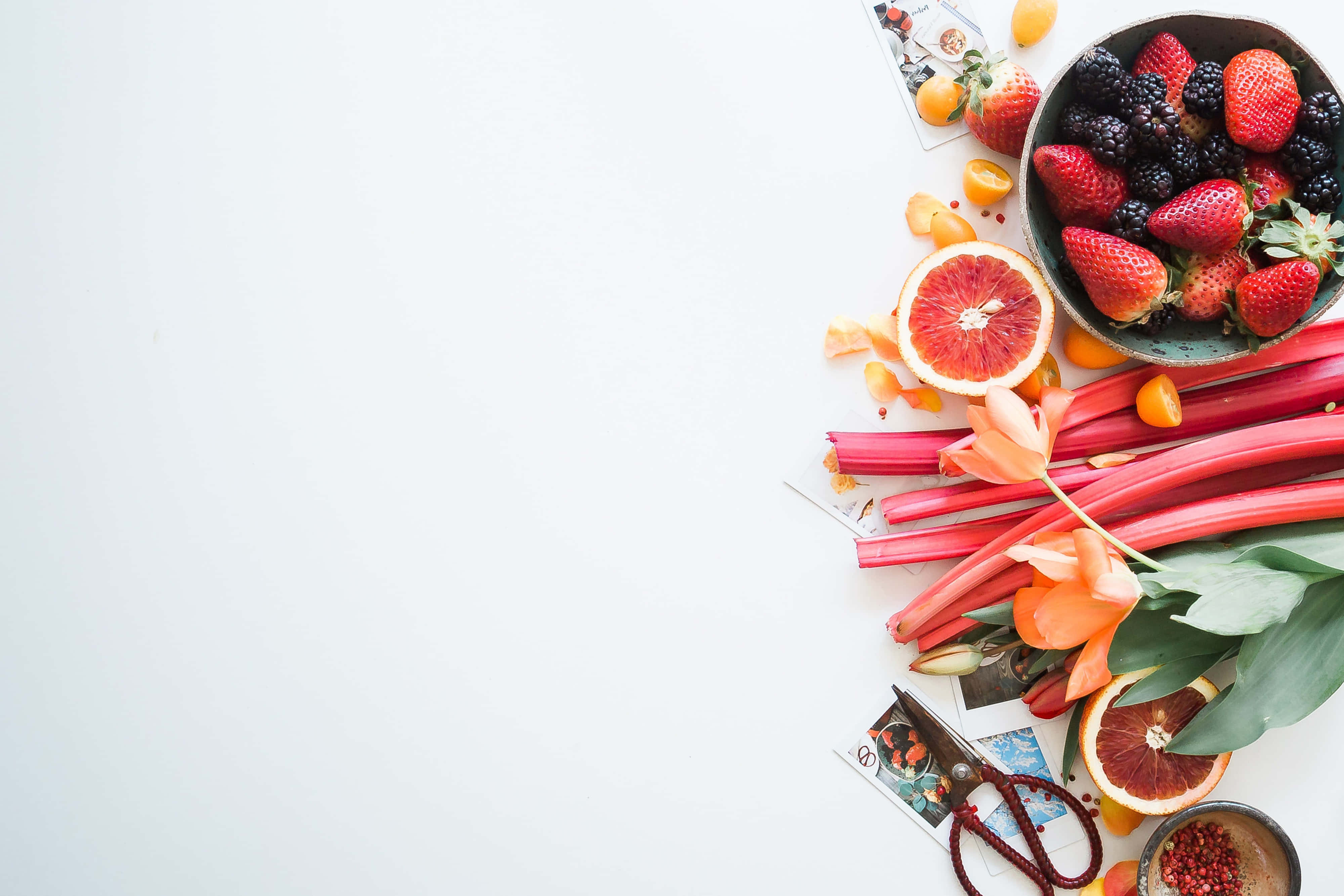 Fruit 桌布 壁紙 — 鮮紅的草莓、黑莓和血橙從碗中溢出，旁邊是大黃和鬱金香，放在潔白的表面上。