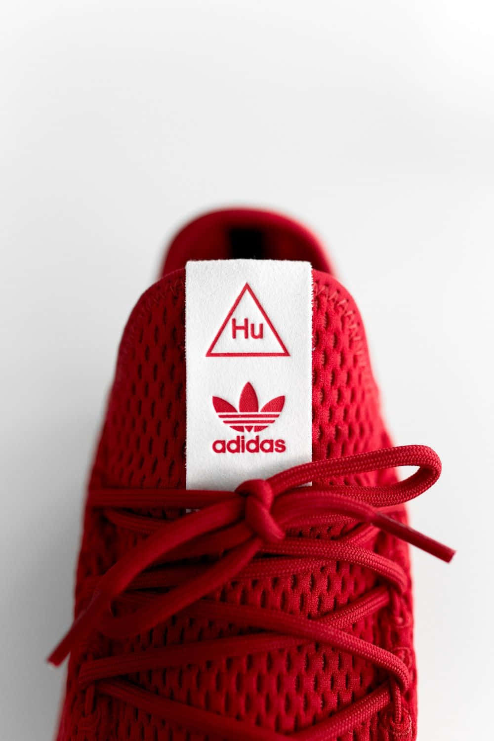 愛迪達 桌布 壁紙 — 鮮紅色Adidas運動鞋特寫，帶有Hu標籤和相配的鞋帶，背景為潔淨白色。