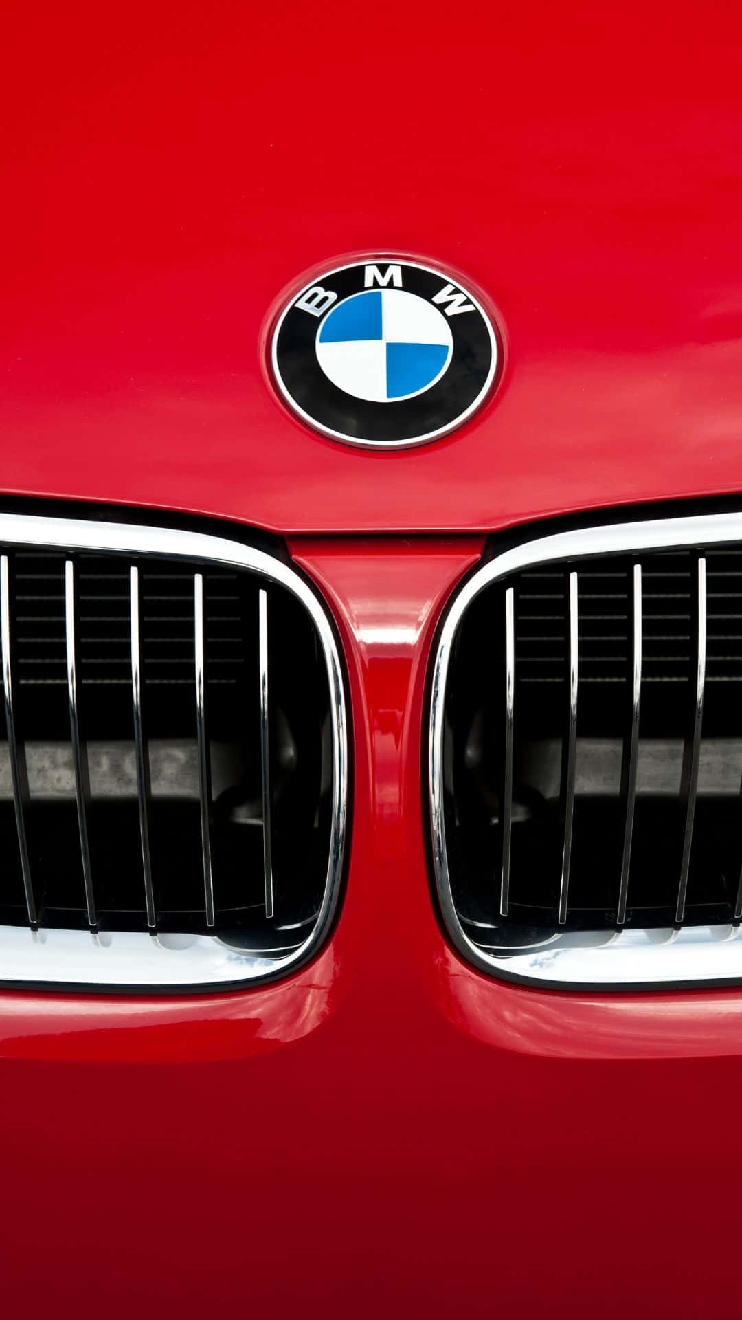 Android Bmw 桌布 壁紙 — 鮮紅色BMW汽車標誌性腎形格柵和圓形標誌的特寫，表面光滑。