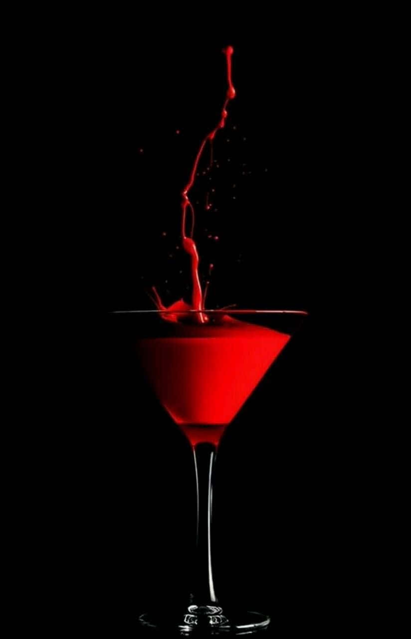 Red Wine Glass 桌布 壁紙 — 鮮紅色的液體從馬丁尼杯中戲劇性地向上飛濺，背景是純黑色。