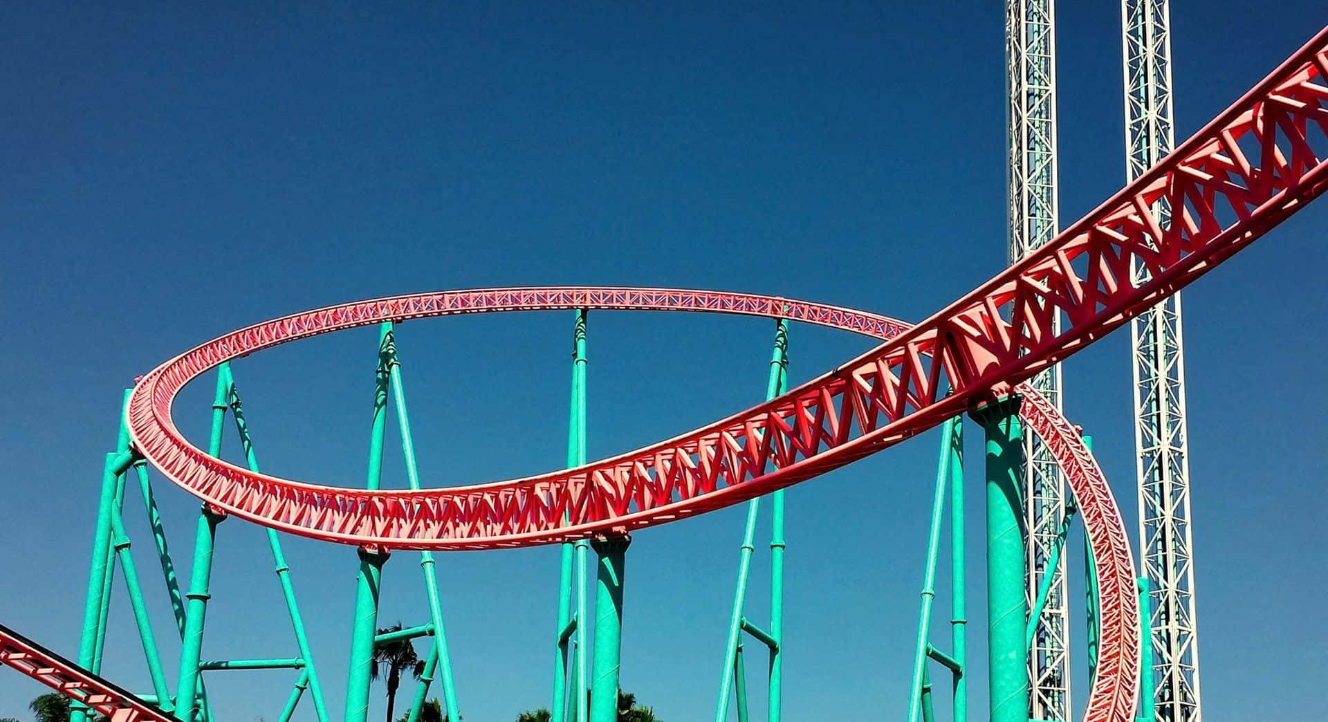 Roller Coaster 桌布 壁紙 — 鮮紅色的雲霄飛車在清澈的藍天下，以綠松石色的支撐樑形成戲劇性的迴圈。