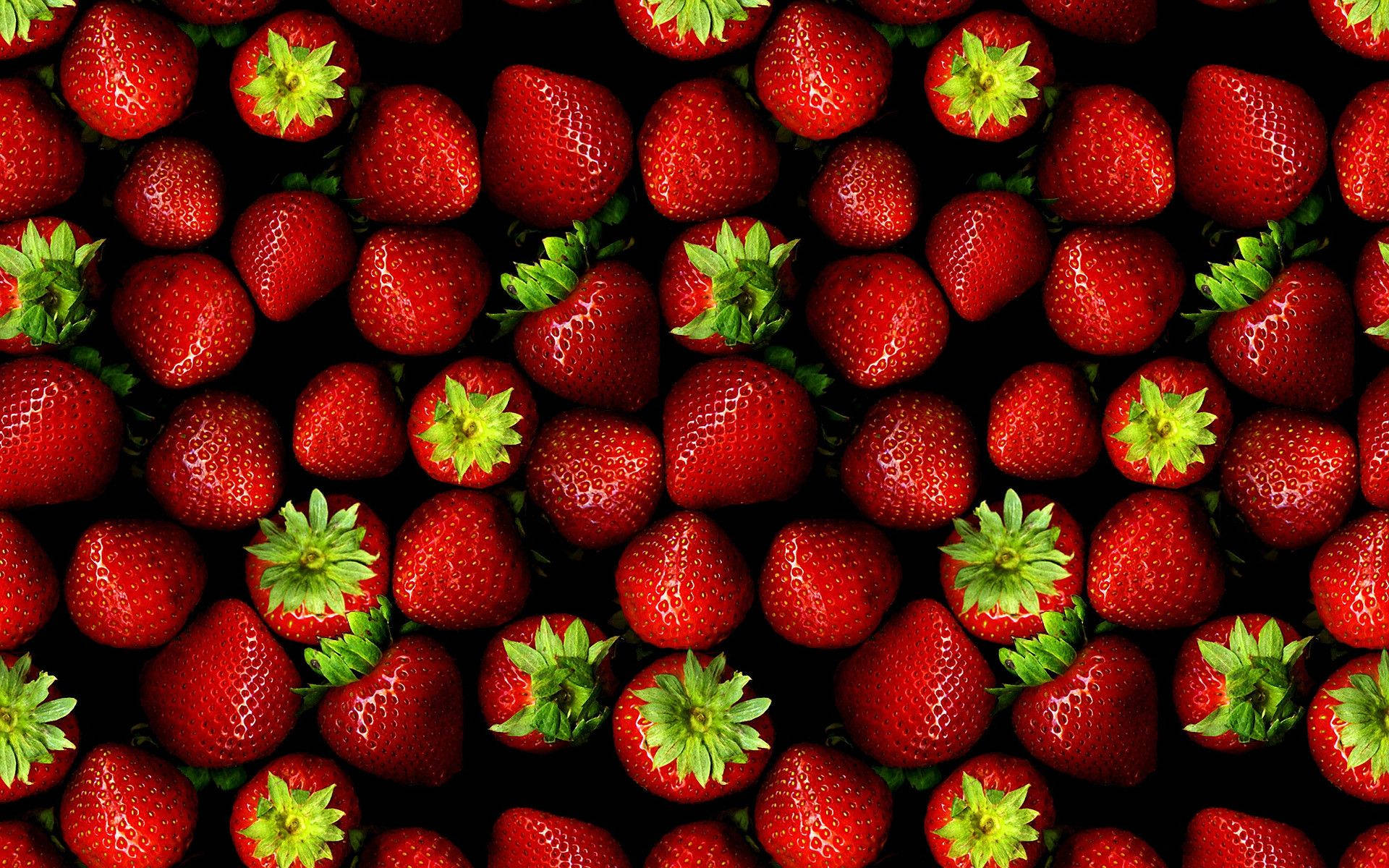 Strawberry Aesthetic 桌布 壁紙 — 鮮紅色草莓，綠色頂部密集排列在黑色背景上。