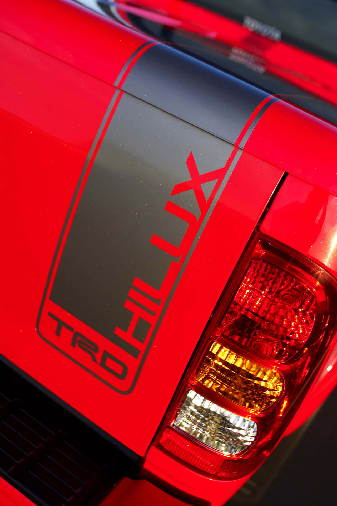 Toyota Logo 桌布 壁紙 — 鮮紅色豐田 Hilux TRD 貨車車尾特寫，展現大膽黑色條紋和發光尾燈。