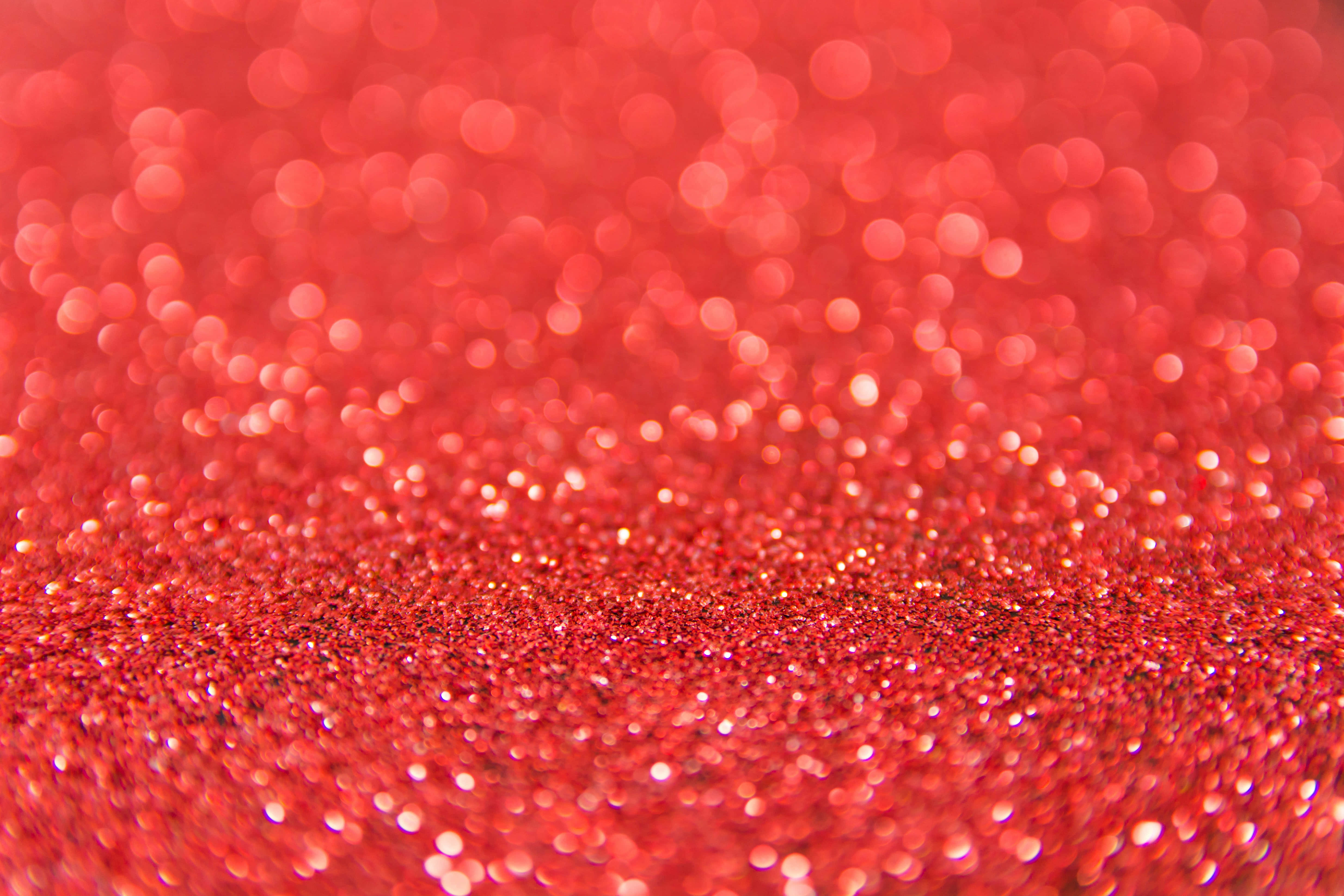 Bokeh 桌布 壁紙 — 鮮紅色閃粉的特寫，帶有散景高光，營造出閃爍的紋理背景。