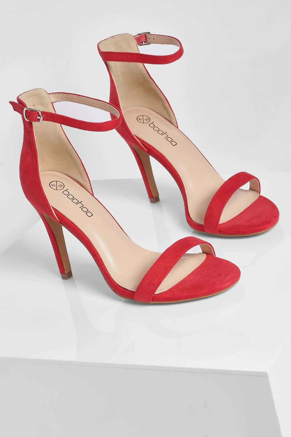 Red High Heels 桌布 壁紙 — 鮮紅色麂皮踝帶高跟鞋，搭配纖細細跟，展示在白色反光表面上。