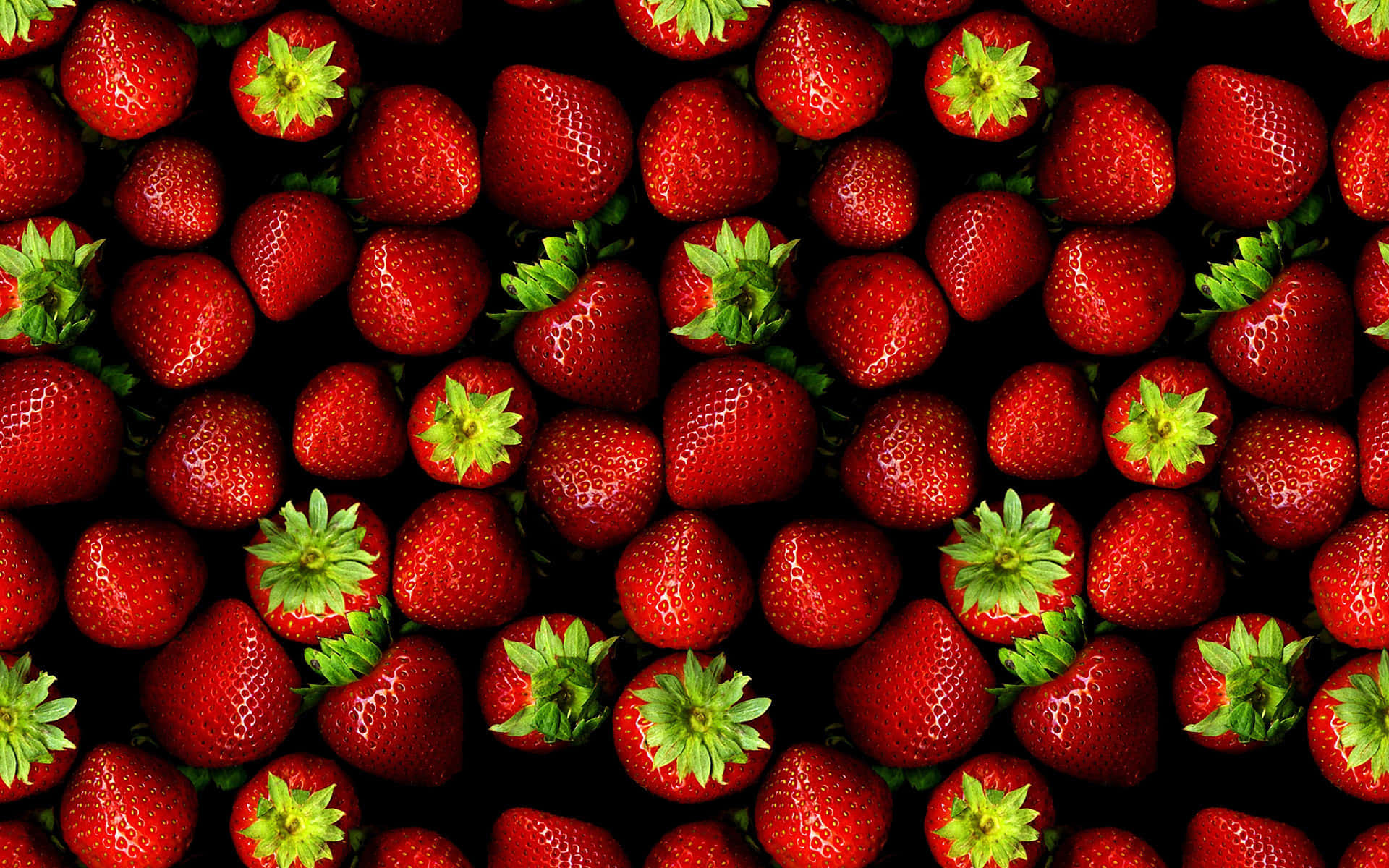 Cute Strawberry 桌布 壁紙 — 鮮紅草莓搭配綠色蒂頭，密集排列在黑色背景上。