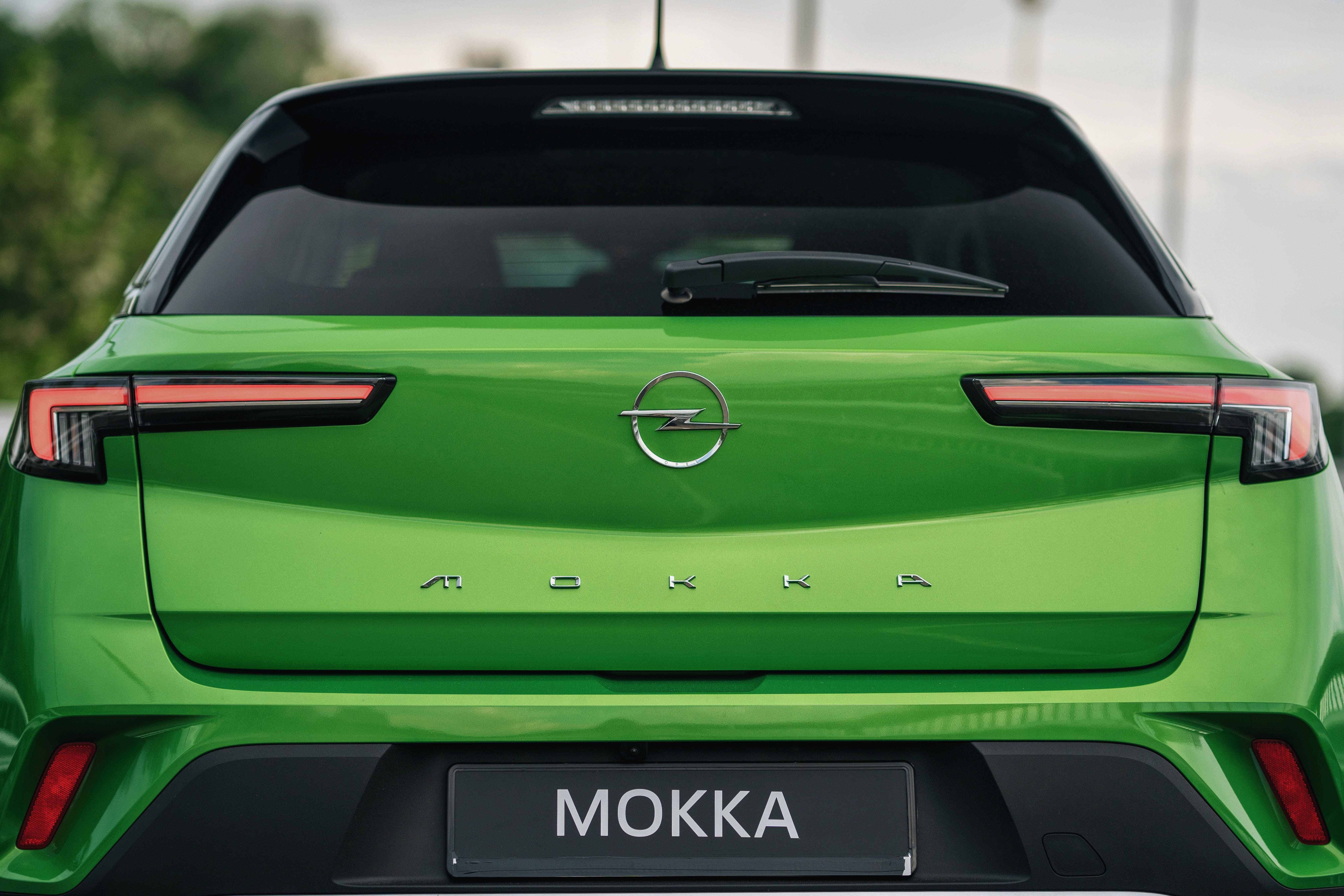 簡約 桌布 壁紙 — 鮮綠色Opel Mokka車尾視角，展現時尚尾燈和鍍鉻標誌，背景柔和模糊。
