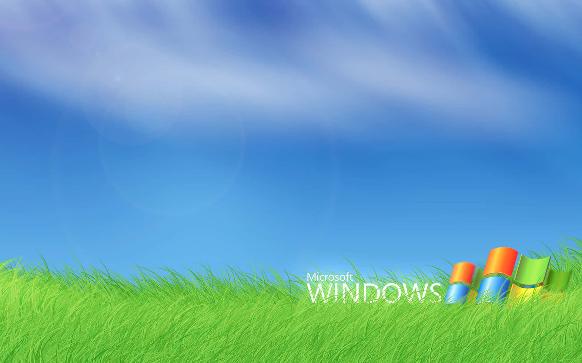 Windows 7 桌布 壁紙 — 鮮綠色草地，清澈藍天下，色彩繽紛的Windows標誌放在山丘邊緣。
